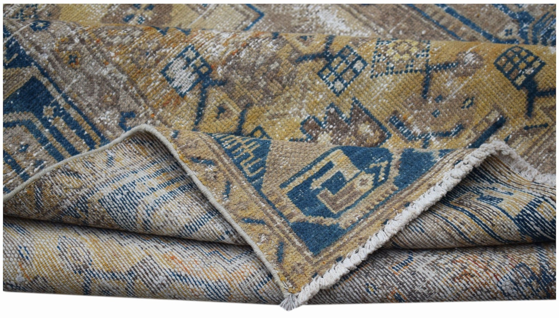 A handwoven vintage Persian rug featuring a distressed geometric pattern in blue and gold tones.