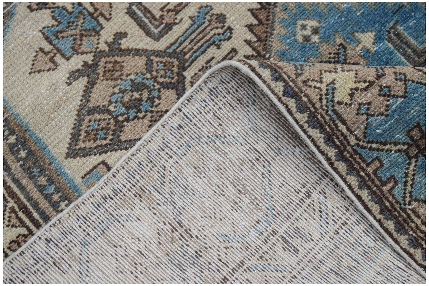 Vintage Persian rug with geometric patterns in blue and beige.