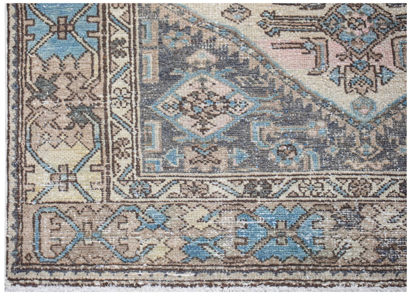 Vintage Persian rug with intricate geometric patterns in blue, pink, and brown.