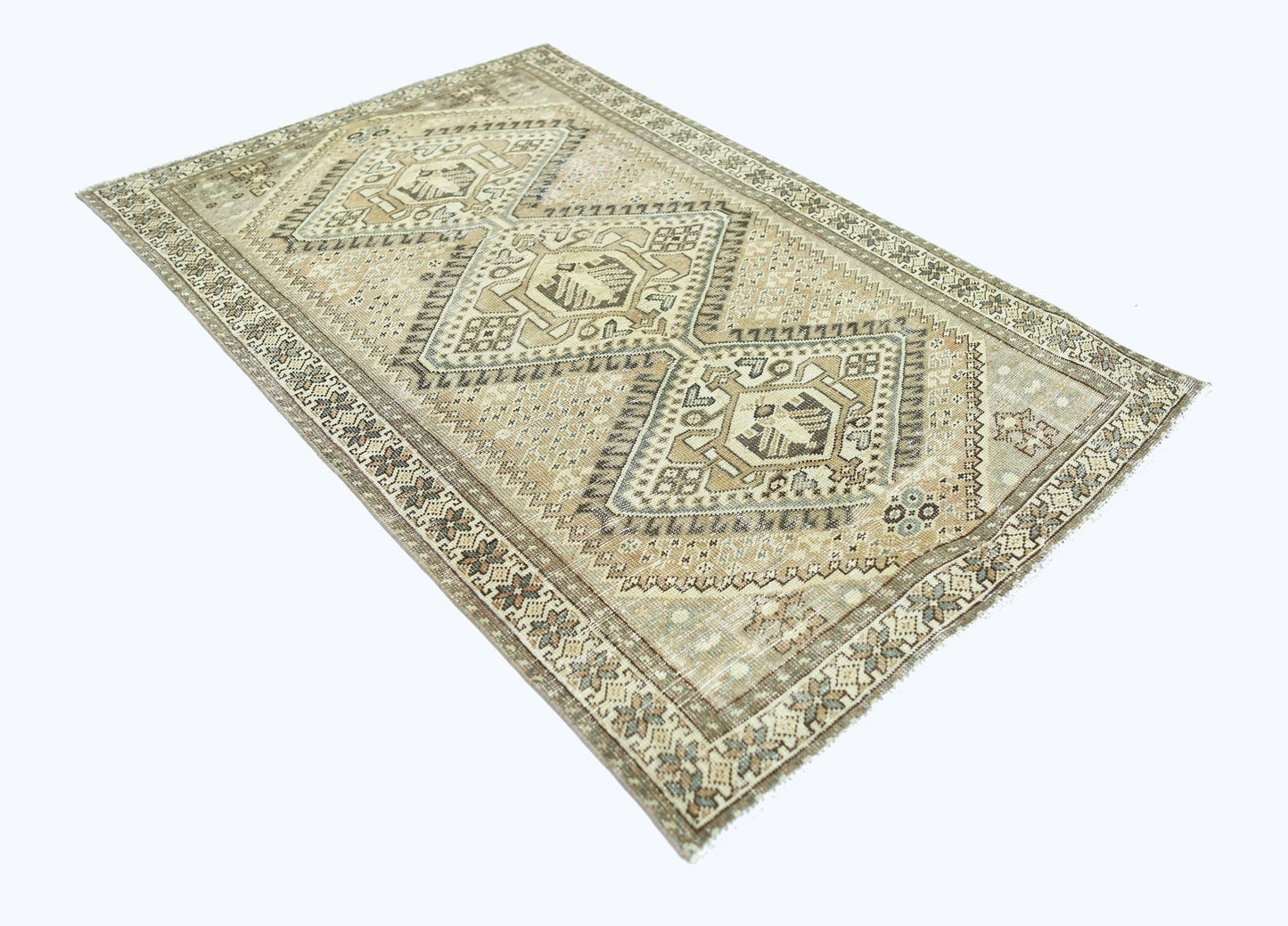 A vintage Persian Qashqai rug featuring geometric diamond medallions in neutral earth tones.