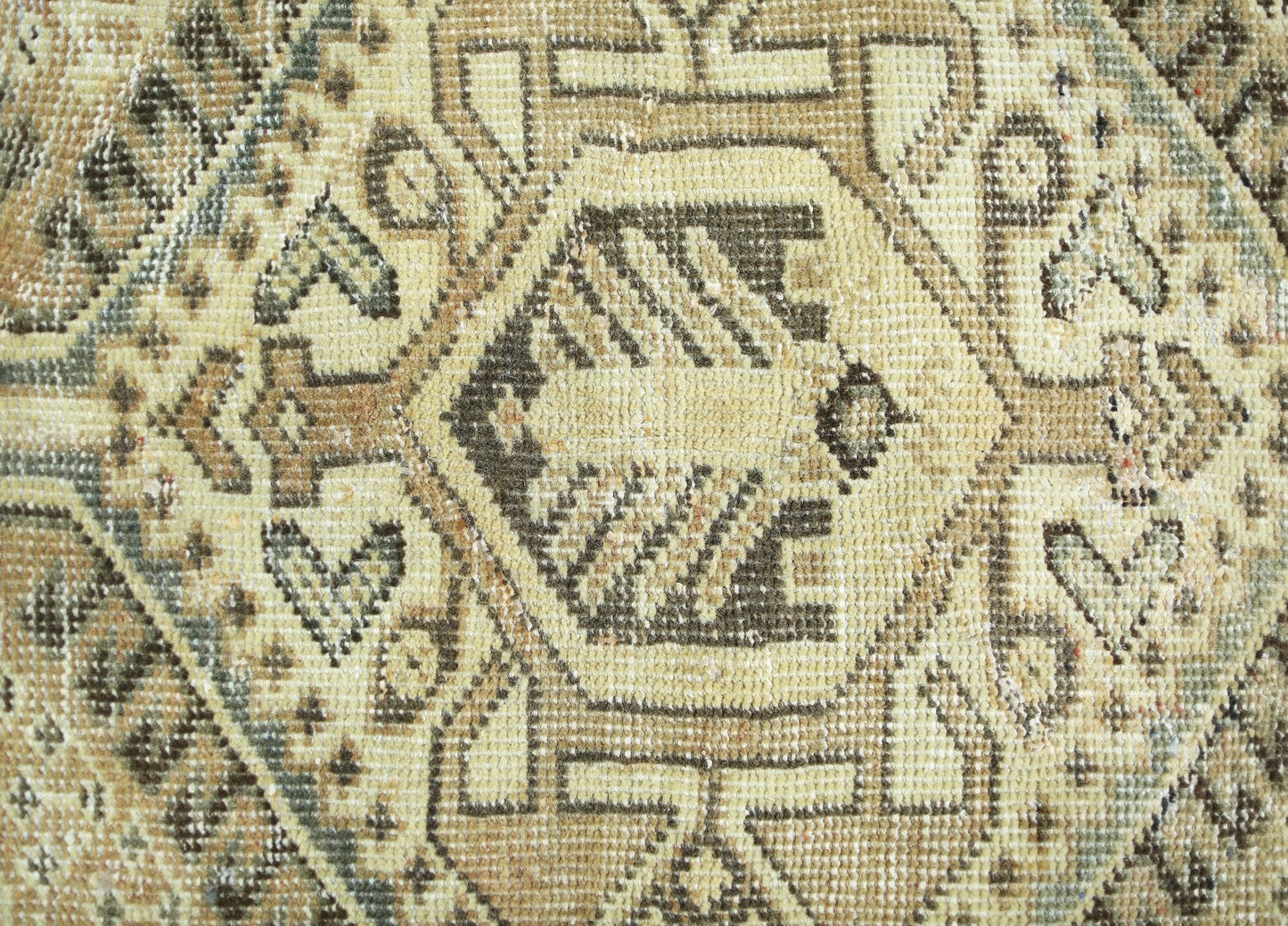 A close-up of a vintage Persian Qashqai rug featuring intricate geometric patterns in neutral tones.