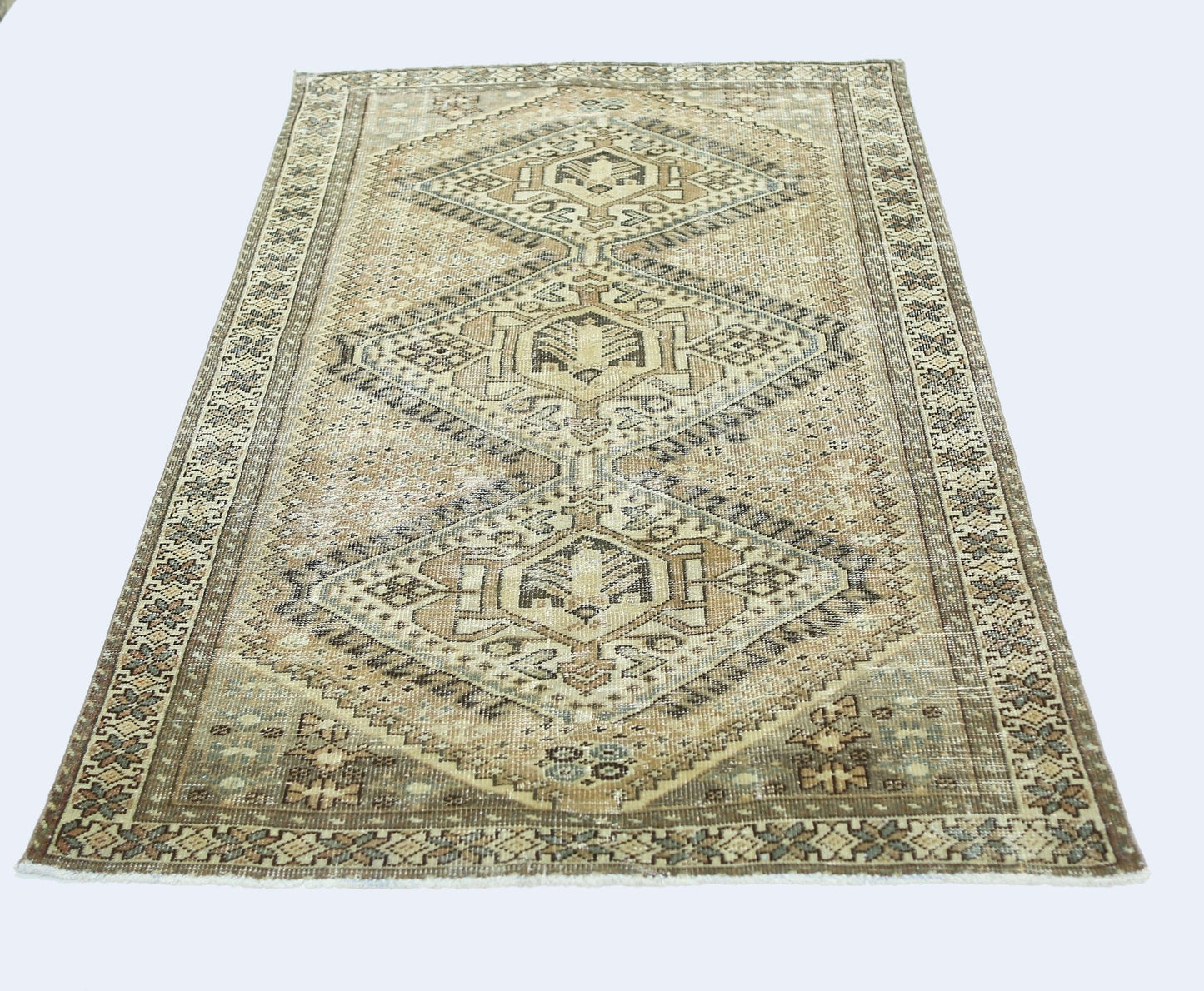 A vintage Persian Qashqai rug featuring a geometric diamond pattern in neutral earth tones.