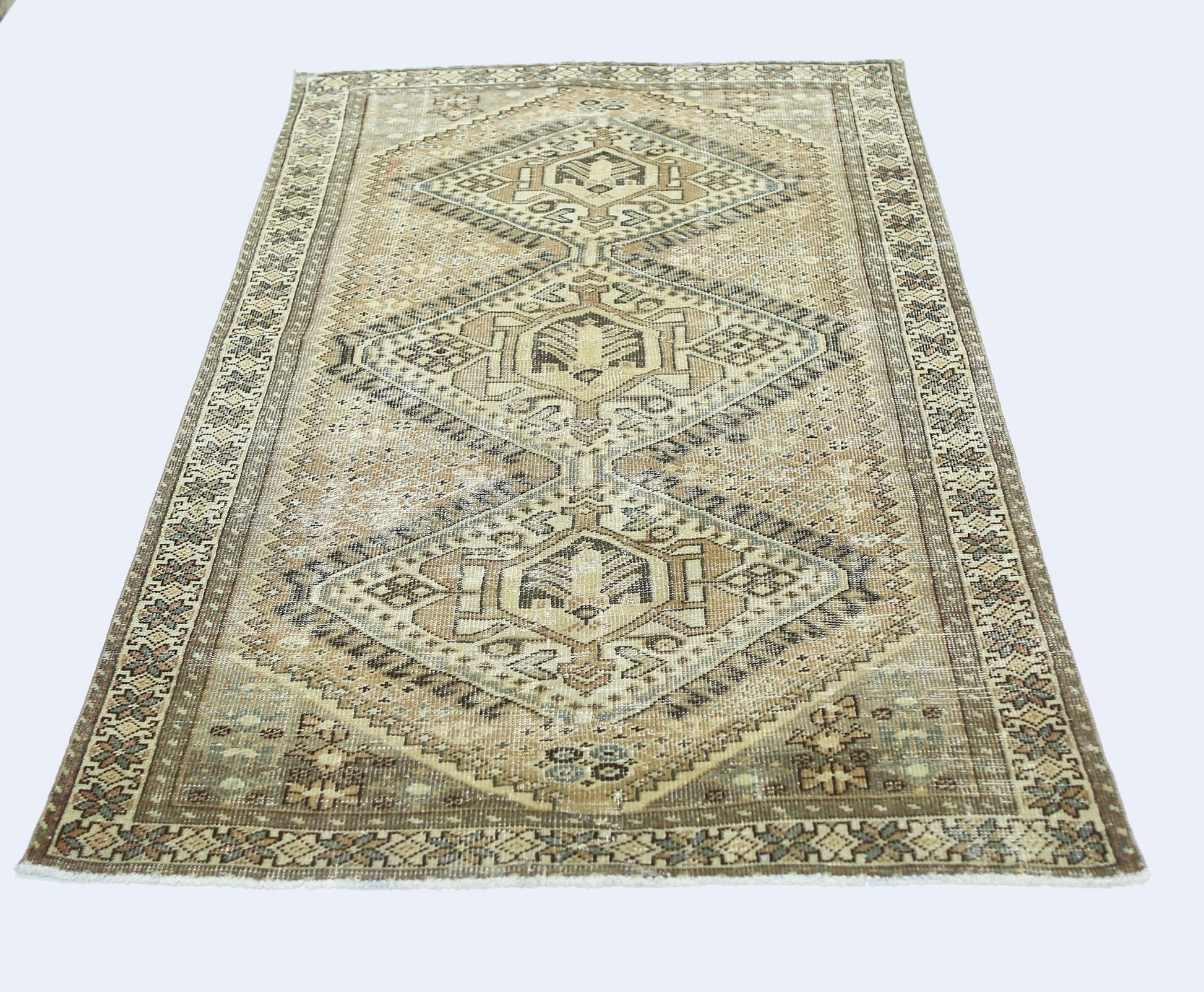A vintage Persian Qashqai rug featuring a geometric diamond pattern in neutral earth tones.