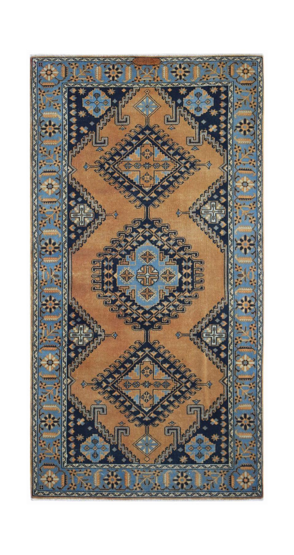 A handwoven vintage Persian rug featuring geometric diamond patterns in blue and tan wool.