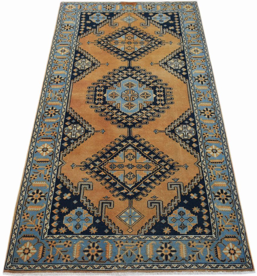 A handwoven vintage Persian rug featuring a geometric pattern in shades of orange and blue.