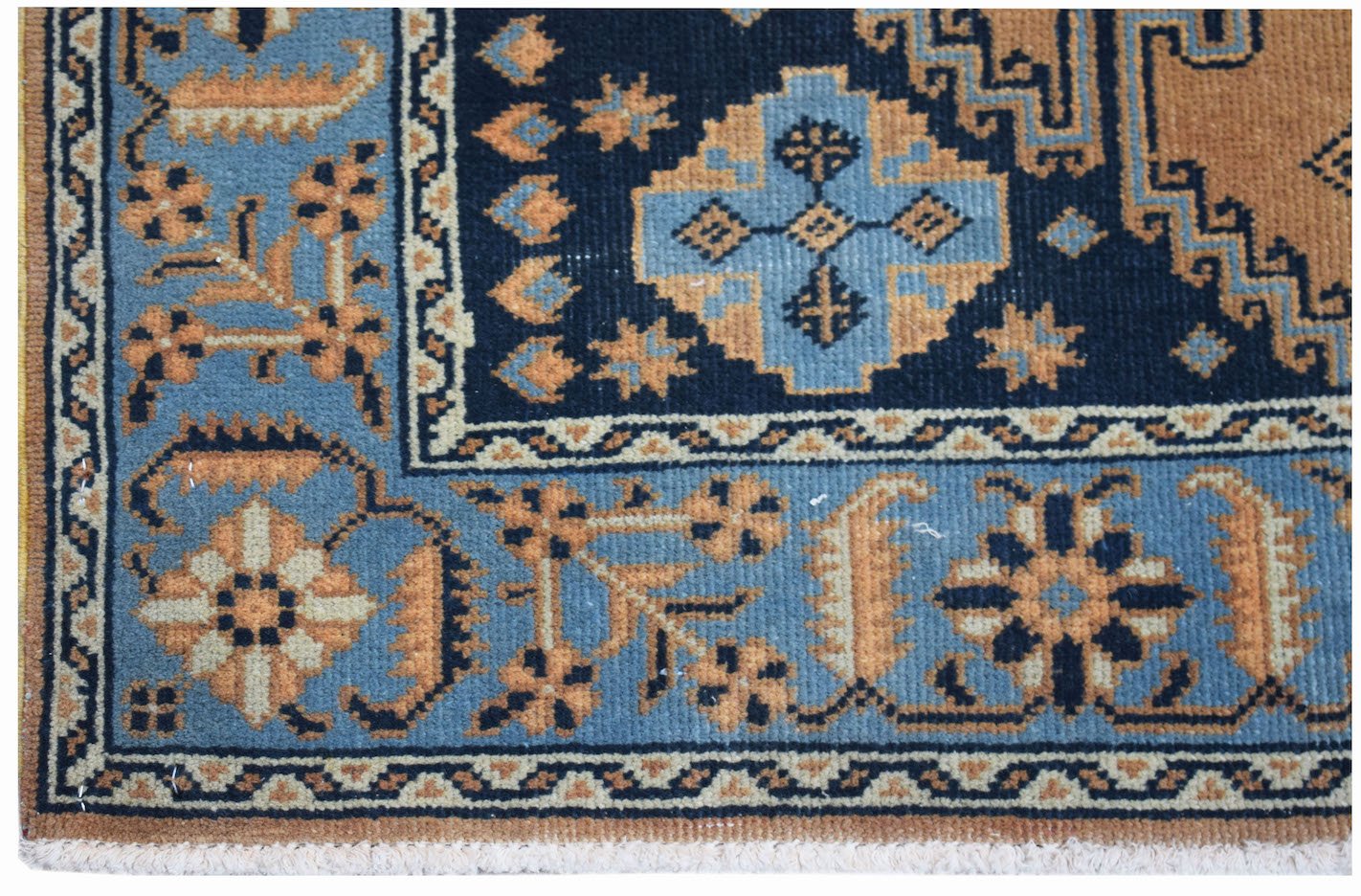 A vintage handwoven Persian rug featuring a geometric floral pattern in blue, tan, and black.