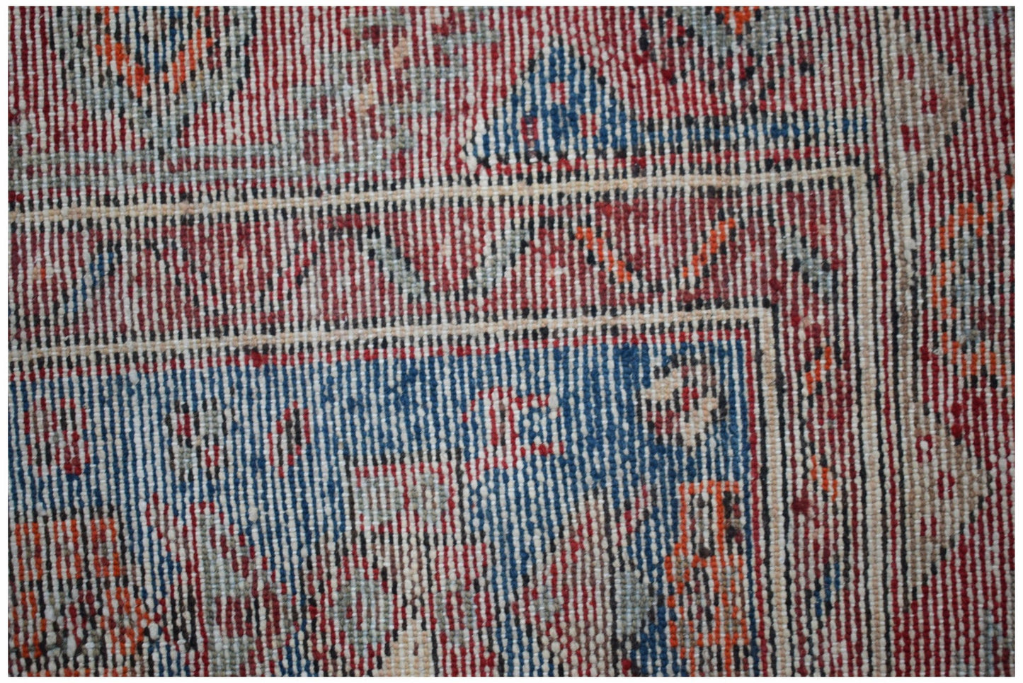A close-up of a handwoven vintage Persian rug featuring intricate geometric patterns in red and blue.