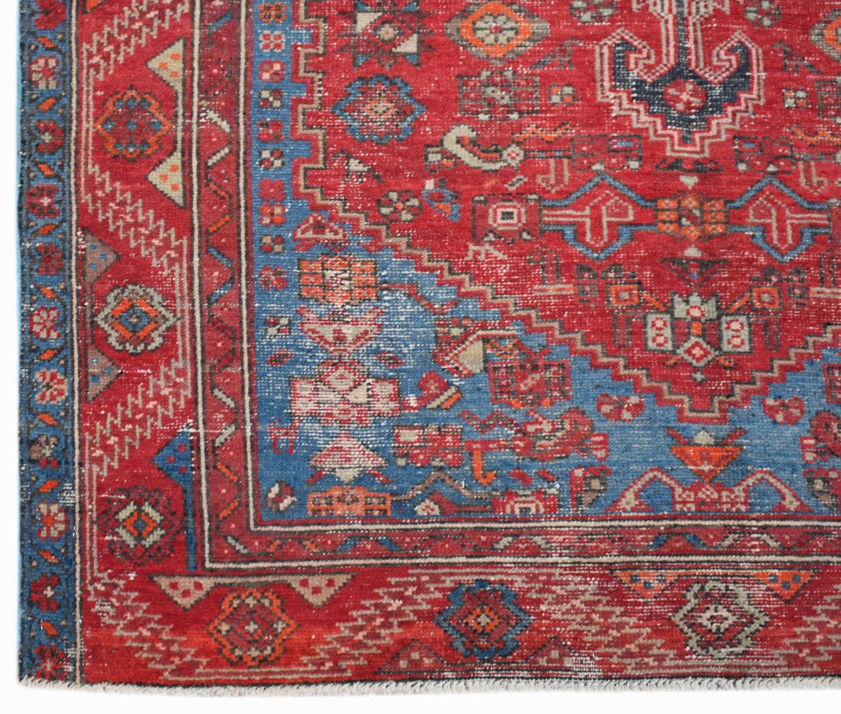 A handwoven vintage Persian rug featuring a geometric pattern in red and blue wool.