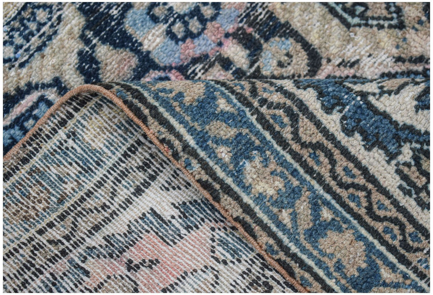 Vintage Persian rug with intricate blue, beige, and pink patterns.