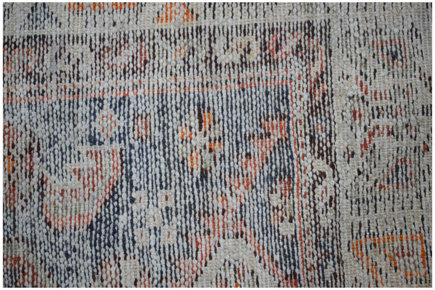 A close-up of a handwoven vintage Persian rug featuring a faded geometric pattern in wool.