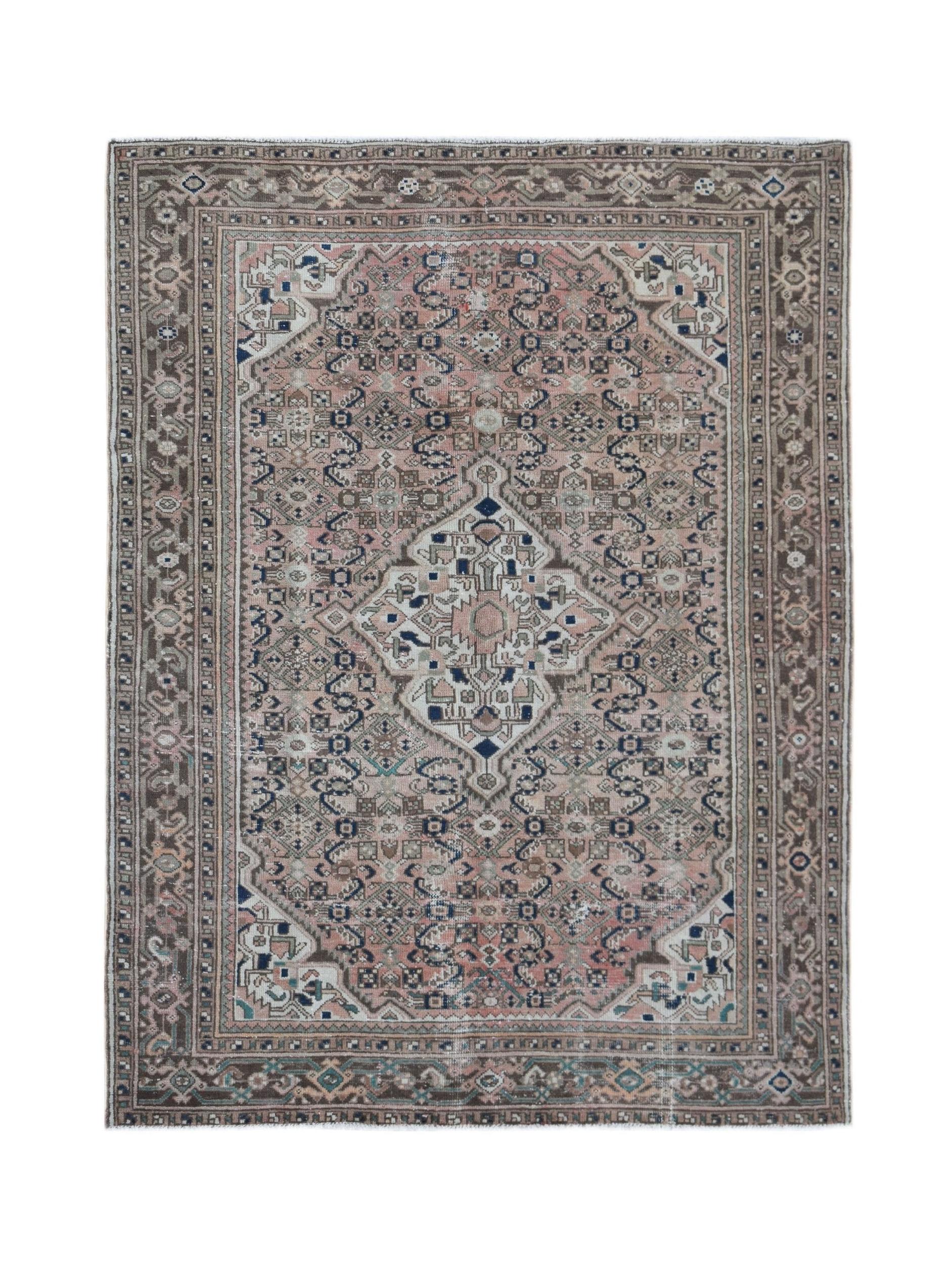 A vintage handwoven Persian rug featuring a central medallion in muted pink, blue, and brown tones.