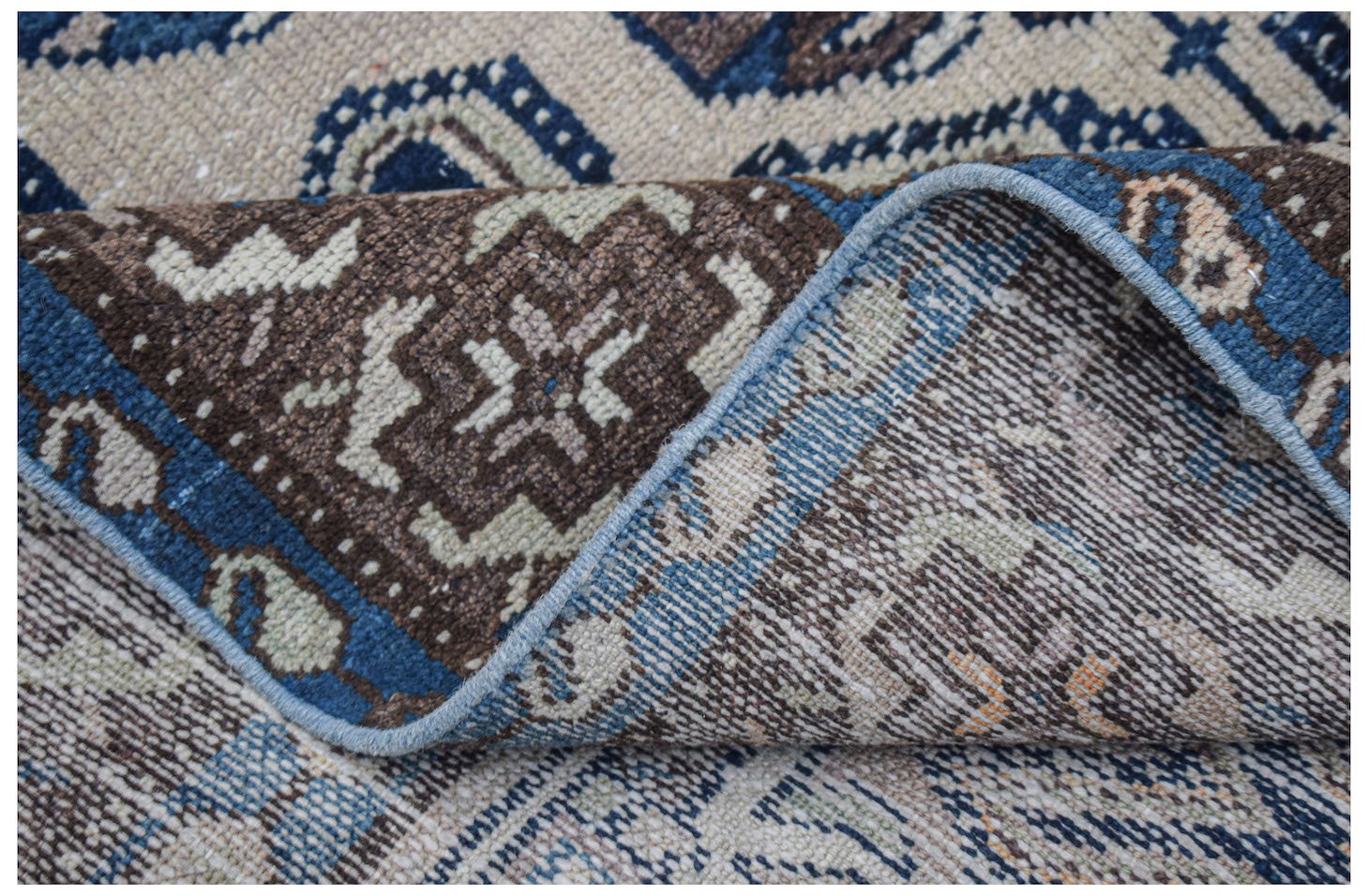 Vintage Persian rug with intricate brown, blue, and beige geometric patterns.