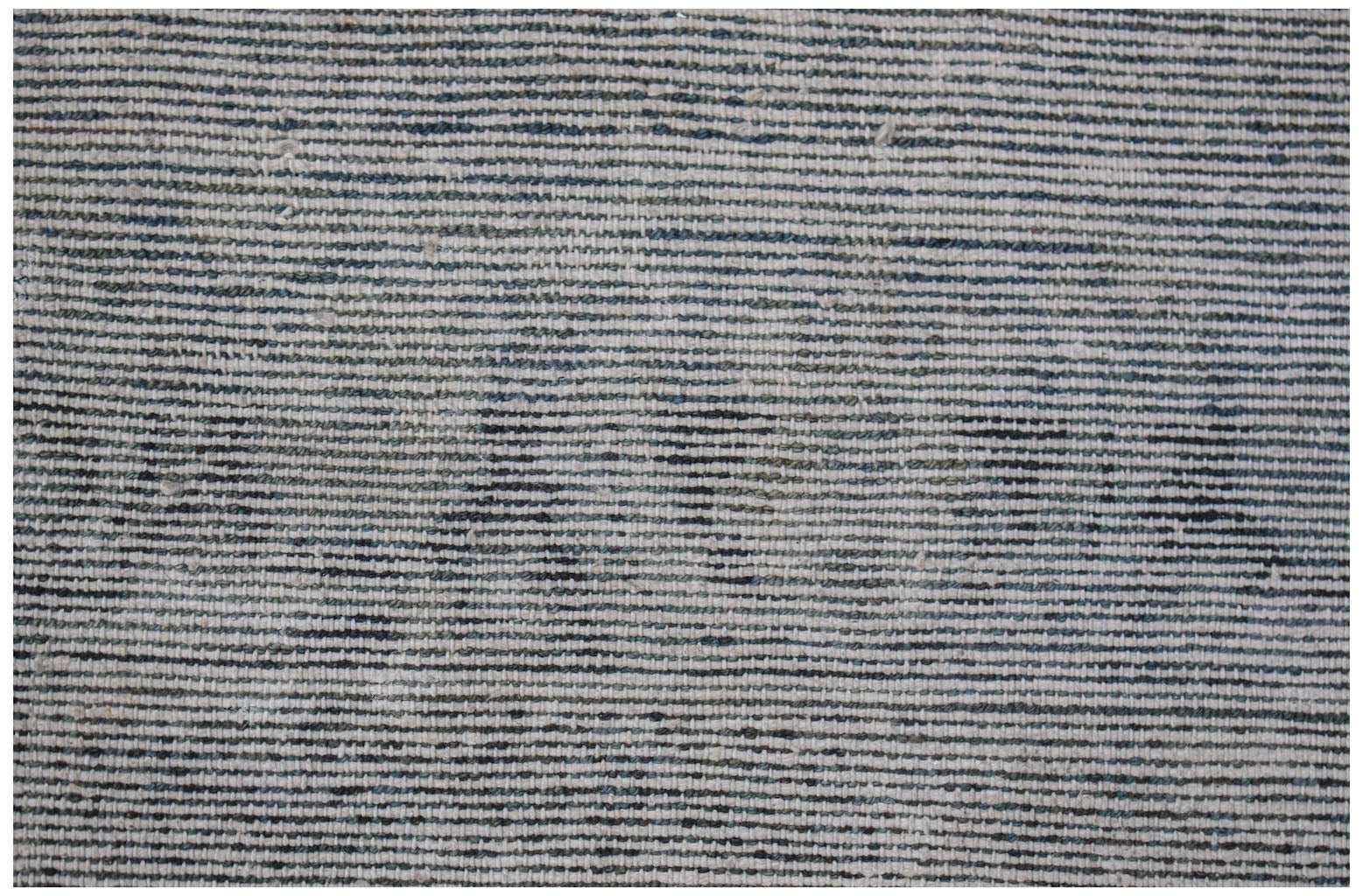 A close-up of a vintage handwoven Turkish rug featuring a textured, striped pattern in muted tones.
