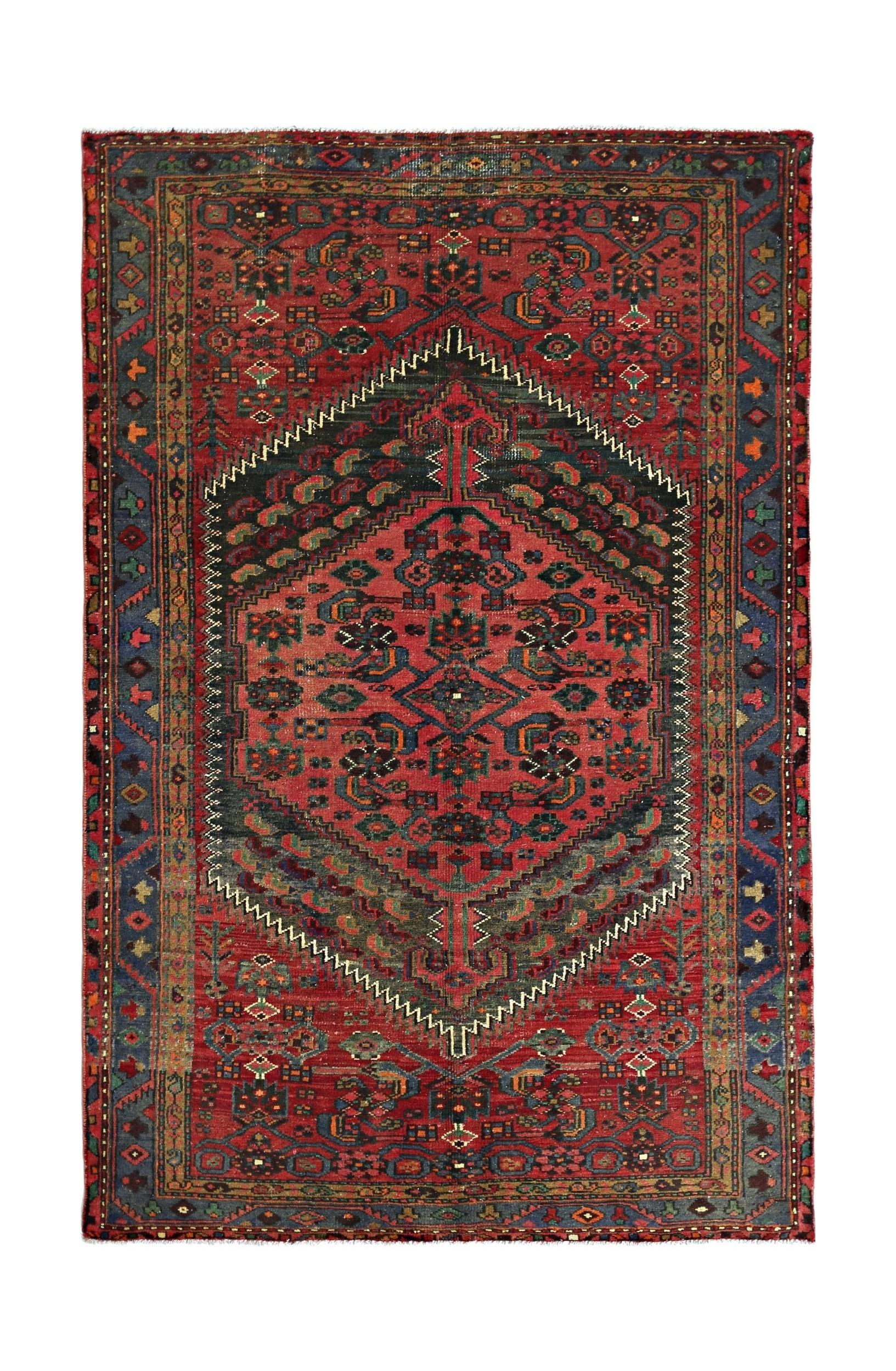 A vintage handmade Persian rug featuring a central geometric medallion on a red field.
