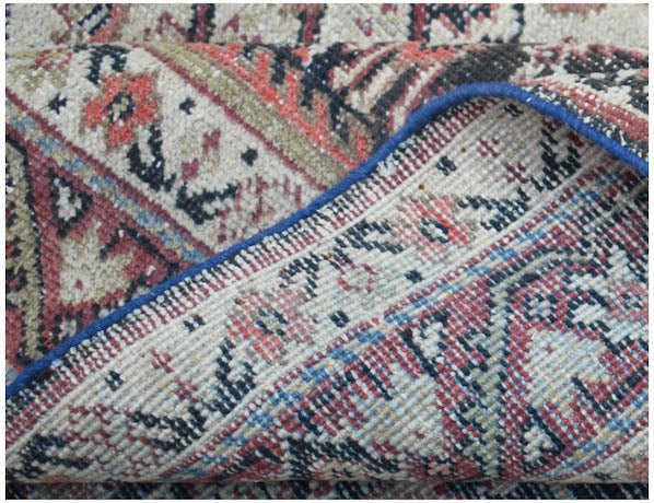 A folded corner of a vintage handwoven Persian rug featuring a traditional floral pattern.