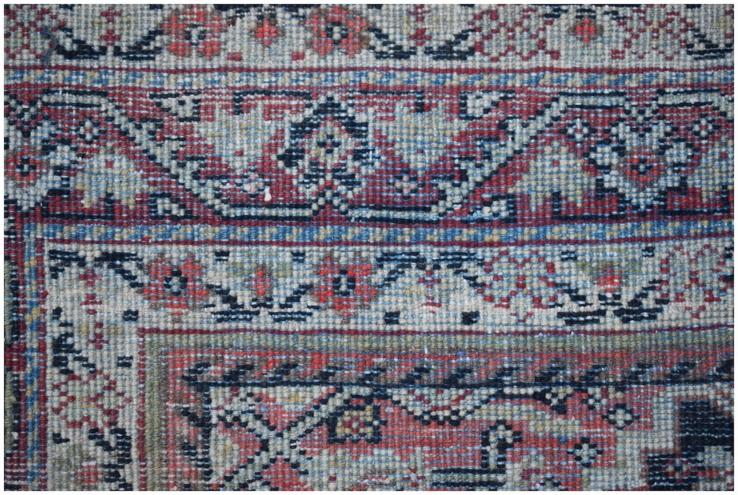 A close-up of a vintage handwoven Persian rug featuring intricate geometric and floral patterns.