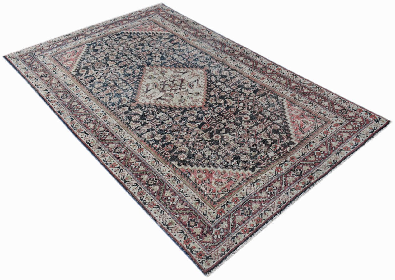 A vintage handwoven Persian rug featuring a dark central medallion and intricate floral patterns.
