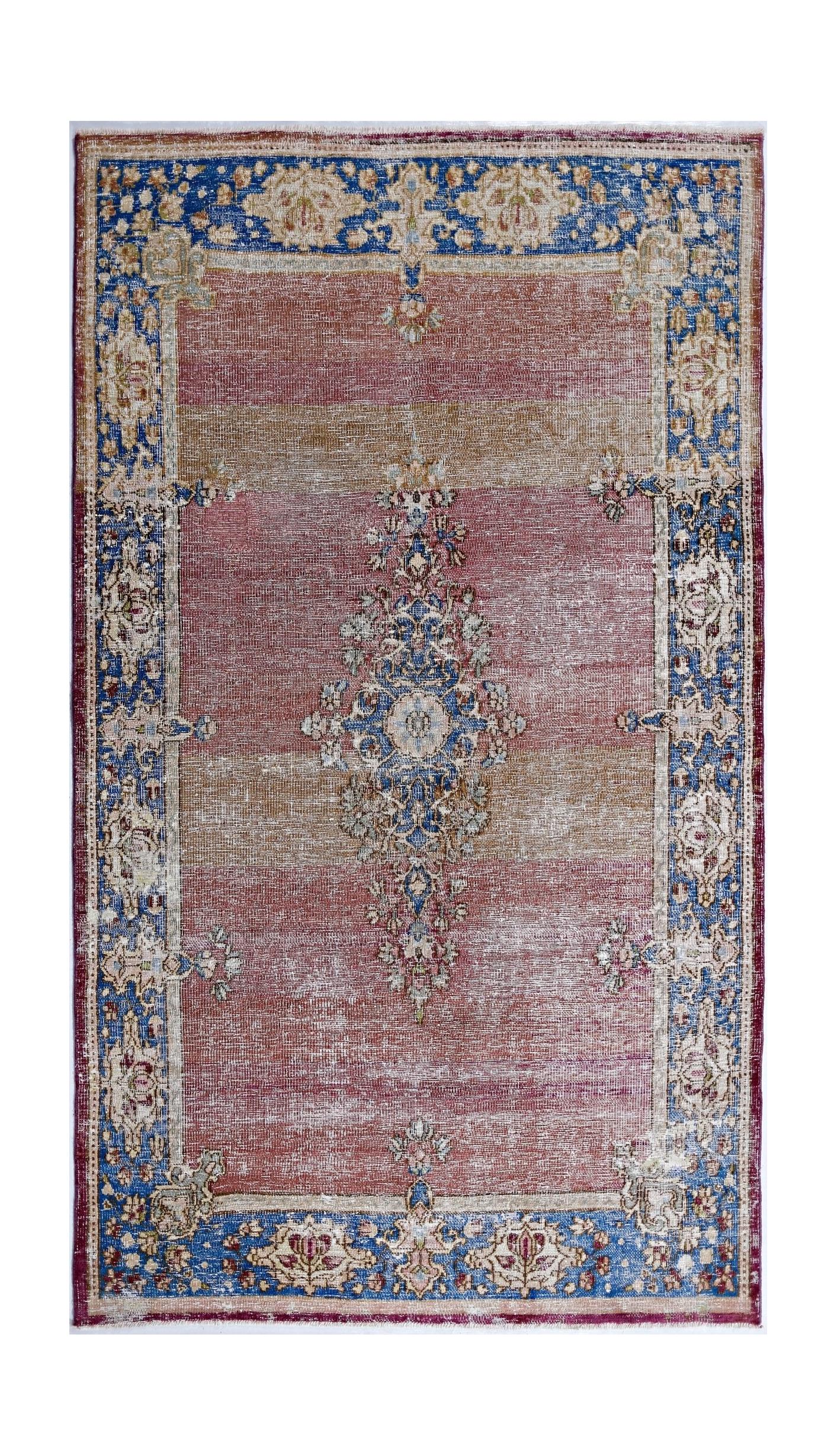 A vintage Persian Kerman rug featuring a central floral medallion on a faded red and tan field.