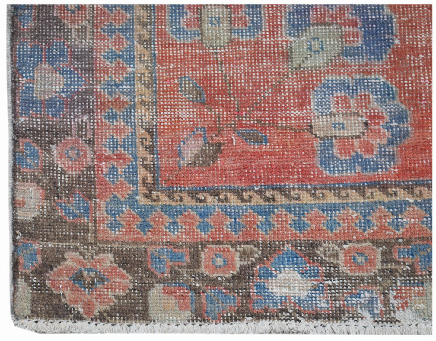 A vintage handwoven Persian rug featuring a floral pattern in red, blue, and brown tones.
