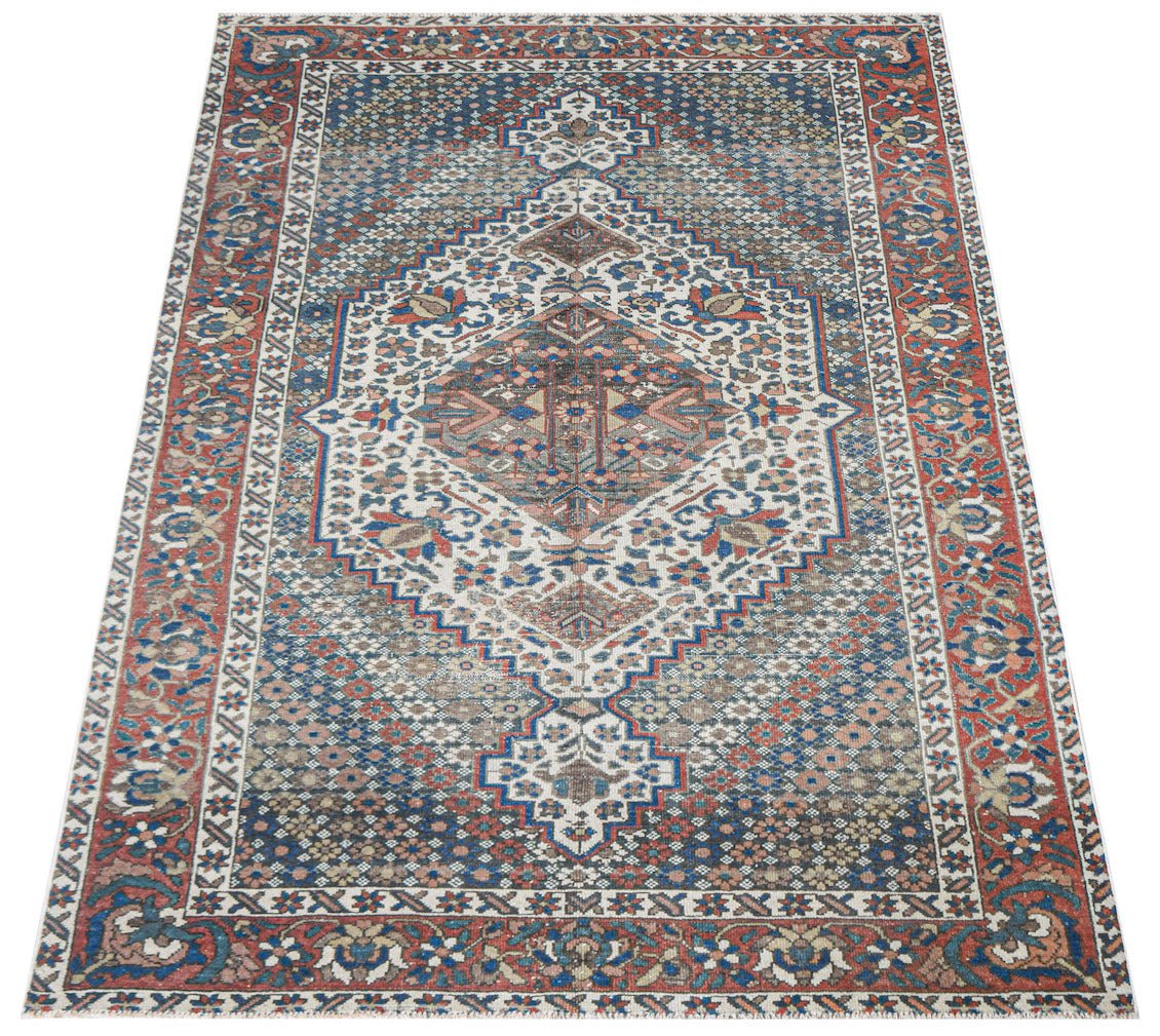 A handwoven vintage Persian rug featuring a central diamond medallion in blue, red, and cream.