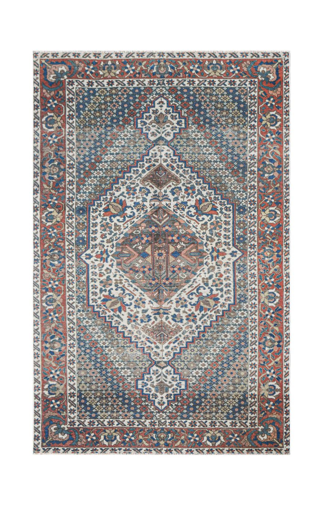 A handwoven vintage Persian rug featuring a central diamond medallion on a blue and cream field.