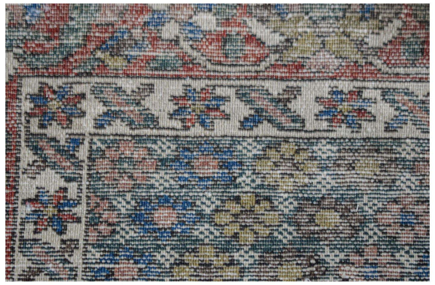 Vintage Persian rug with floral patterns in red, blue, and green.