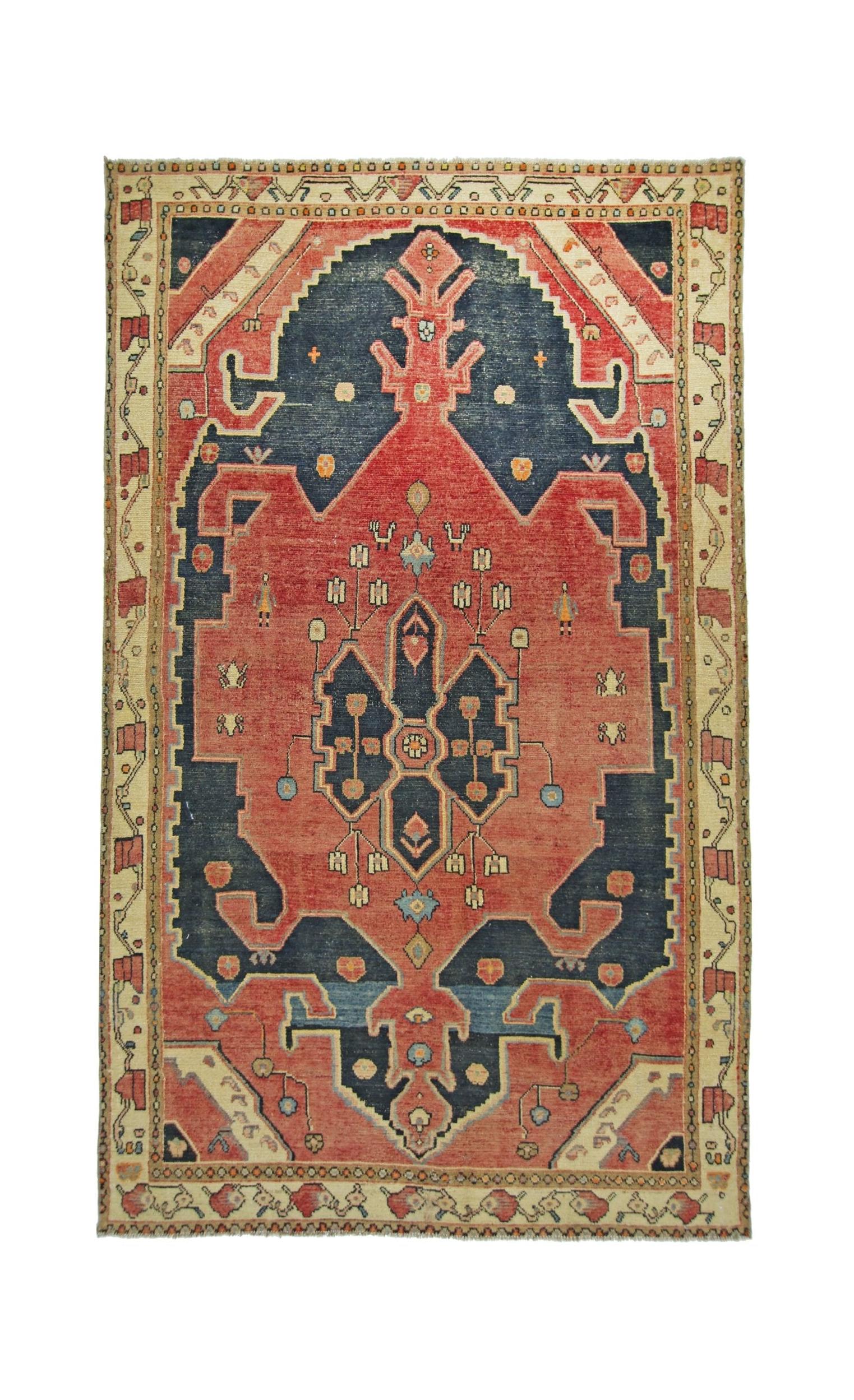 A vintage handmade Persian rug featuring a geometric medallion pattern in red and navy blue.