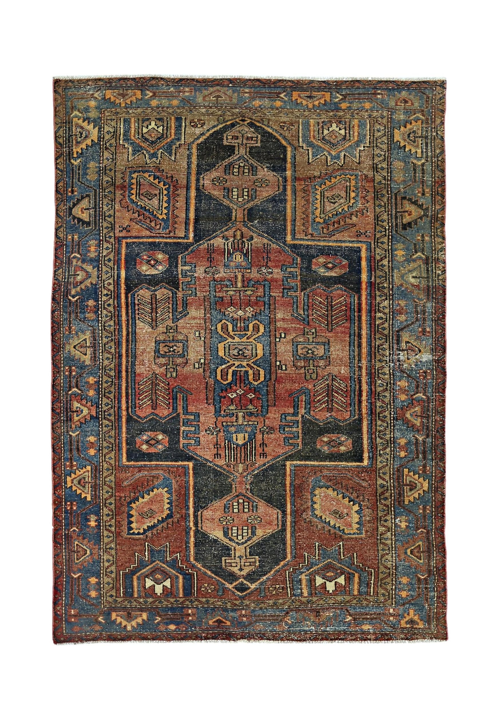 A vintage handmade Persian rug featuring a geometric medallion pattern in red, blue, and tan.