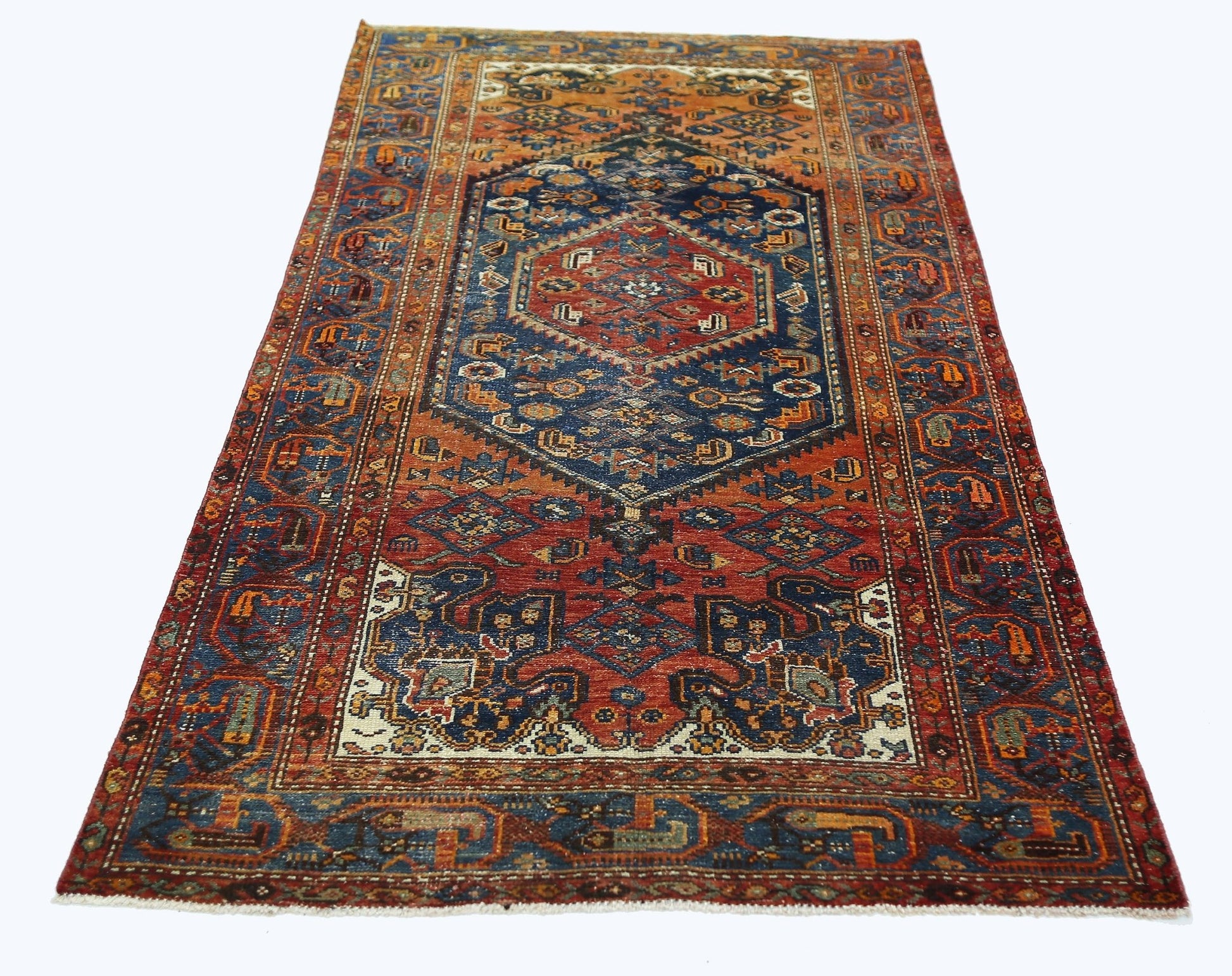 A vintage Persian rug featuring a central blue medallion and intricate geometric patterns in red.