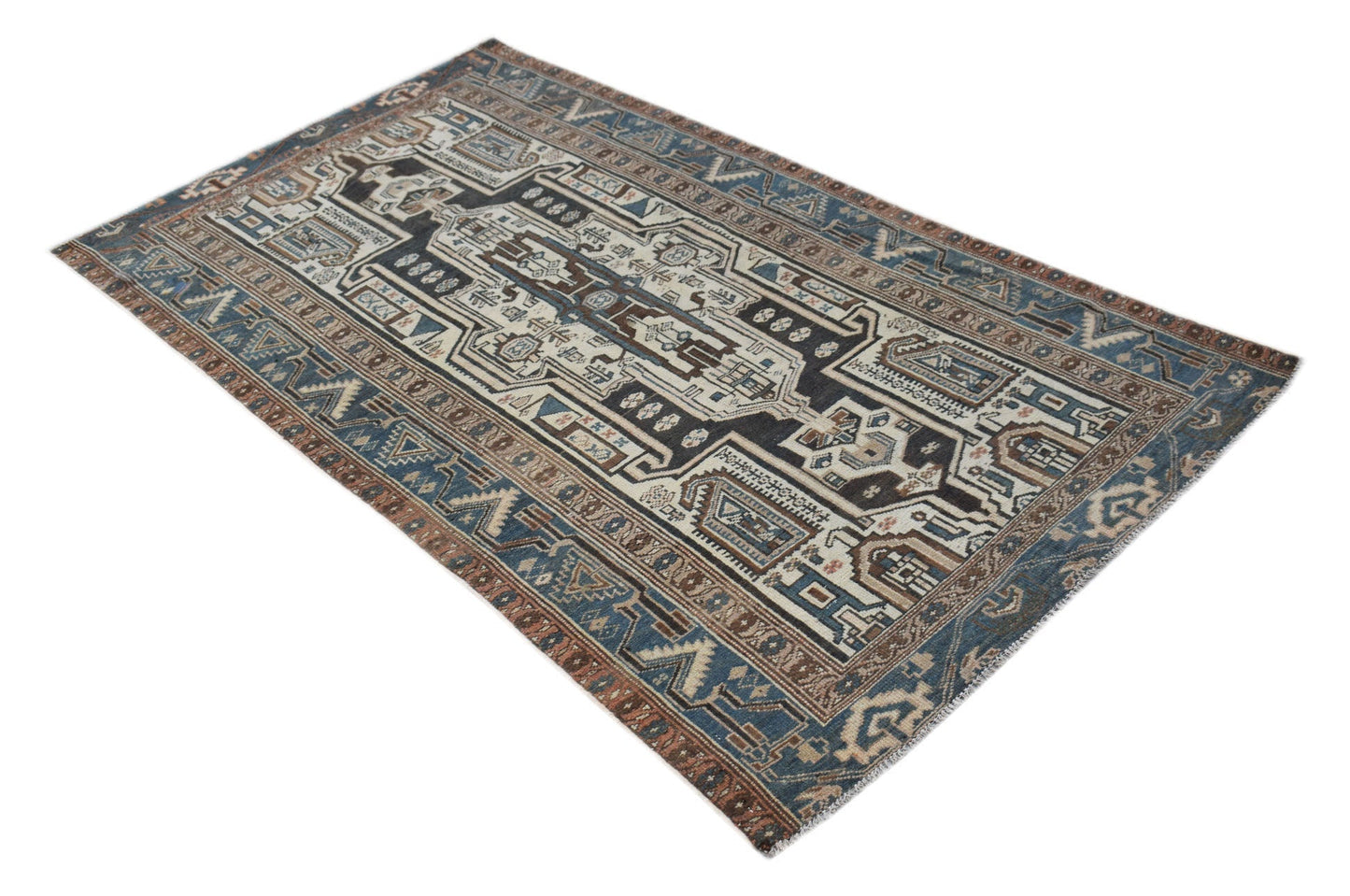 A handwoven vintage Persian rug featuring a geometric pattern in shades of blue, brown, and cream.