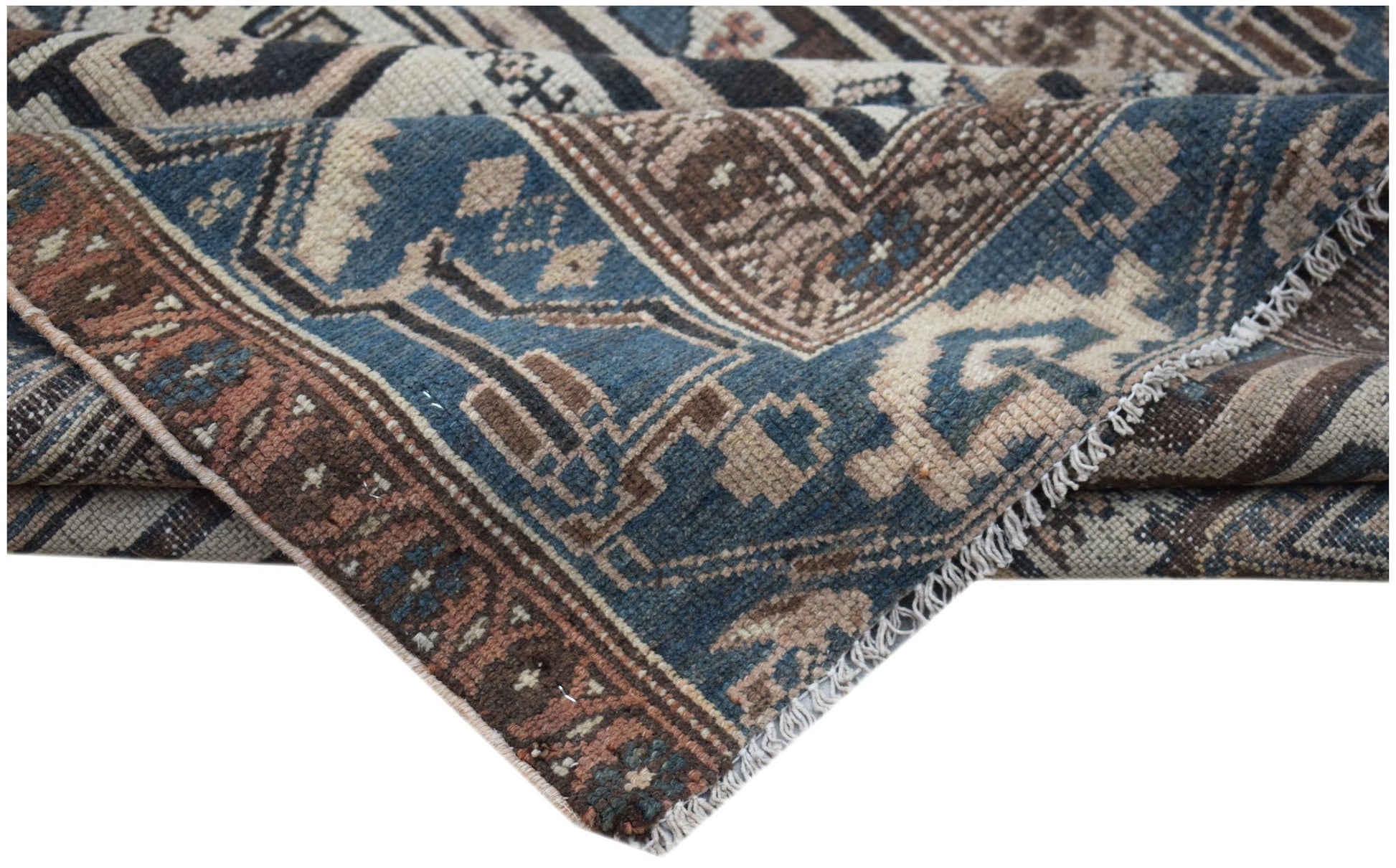 A handwoven vintage Persian rug featuring geometric patterns in shades of blue, brown, and cream.