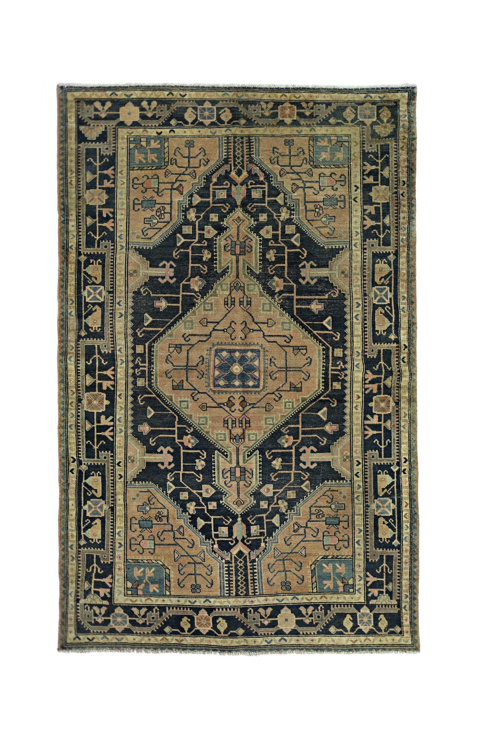 A vintage handmade Persian rug featuring a dark blue central medallion on a tan field.