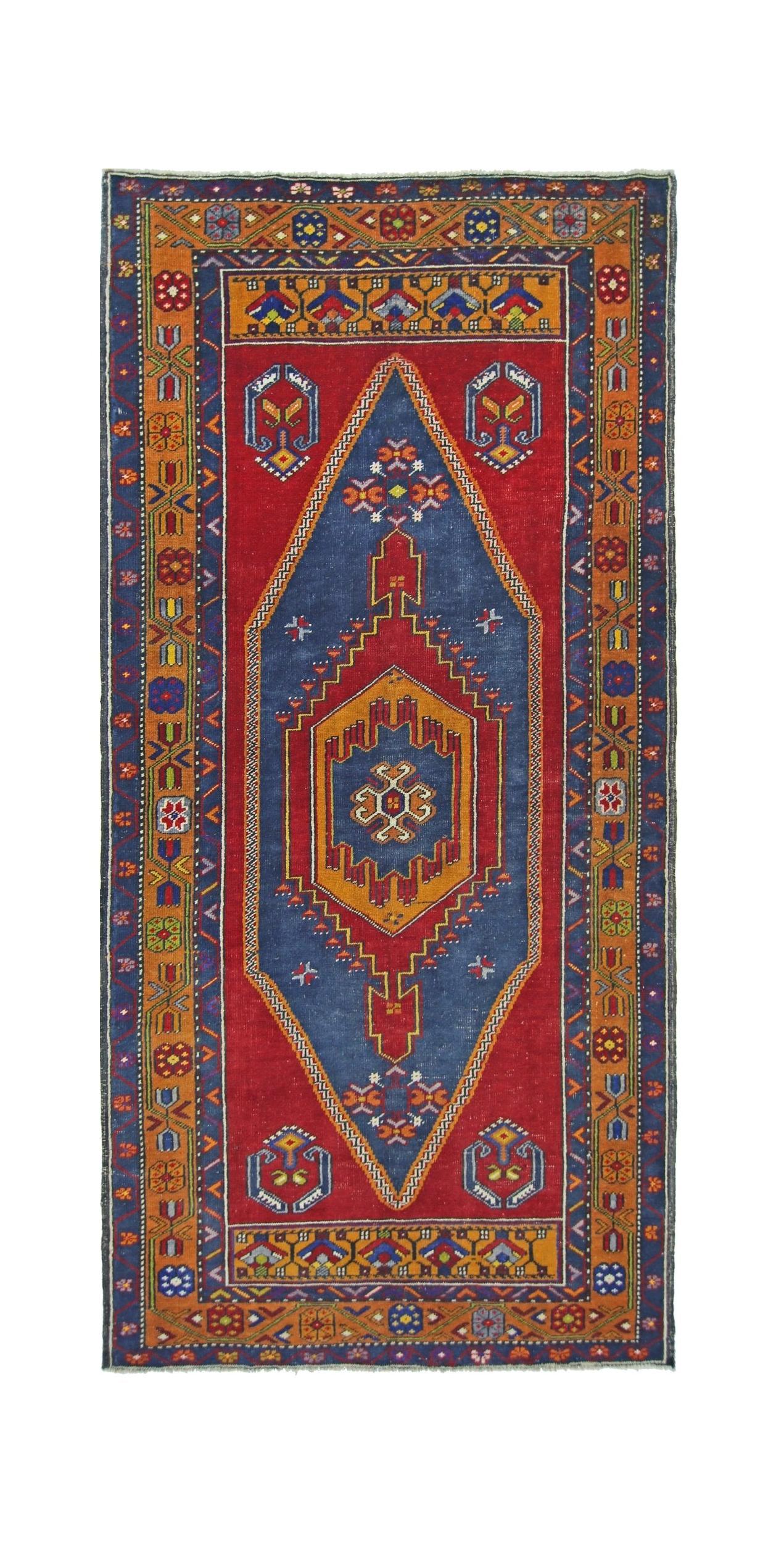 A vintage handmade Turkish Taspinar rug featuring a central blue diamond medallion on a red field.