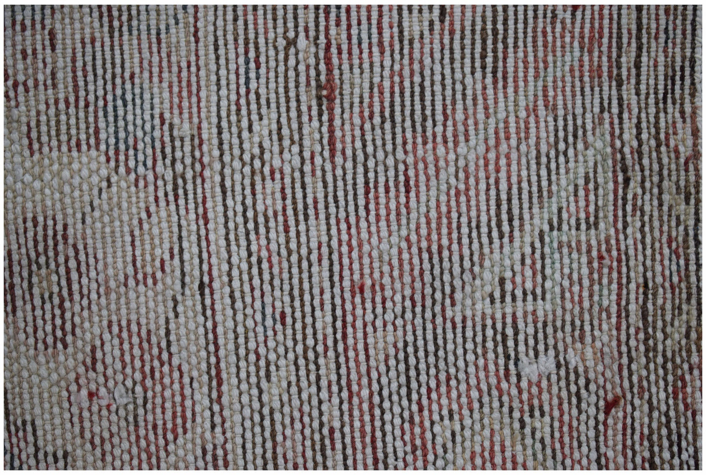 A close-up view of a vintage Persian rug featuring a textured, handwoven pattern in faded tones.
