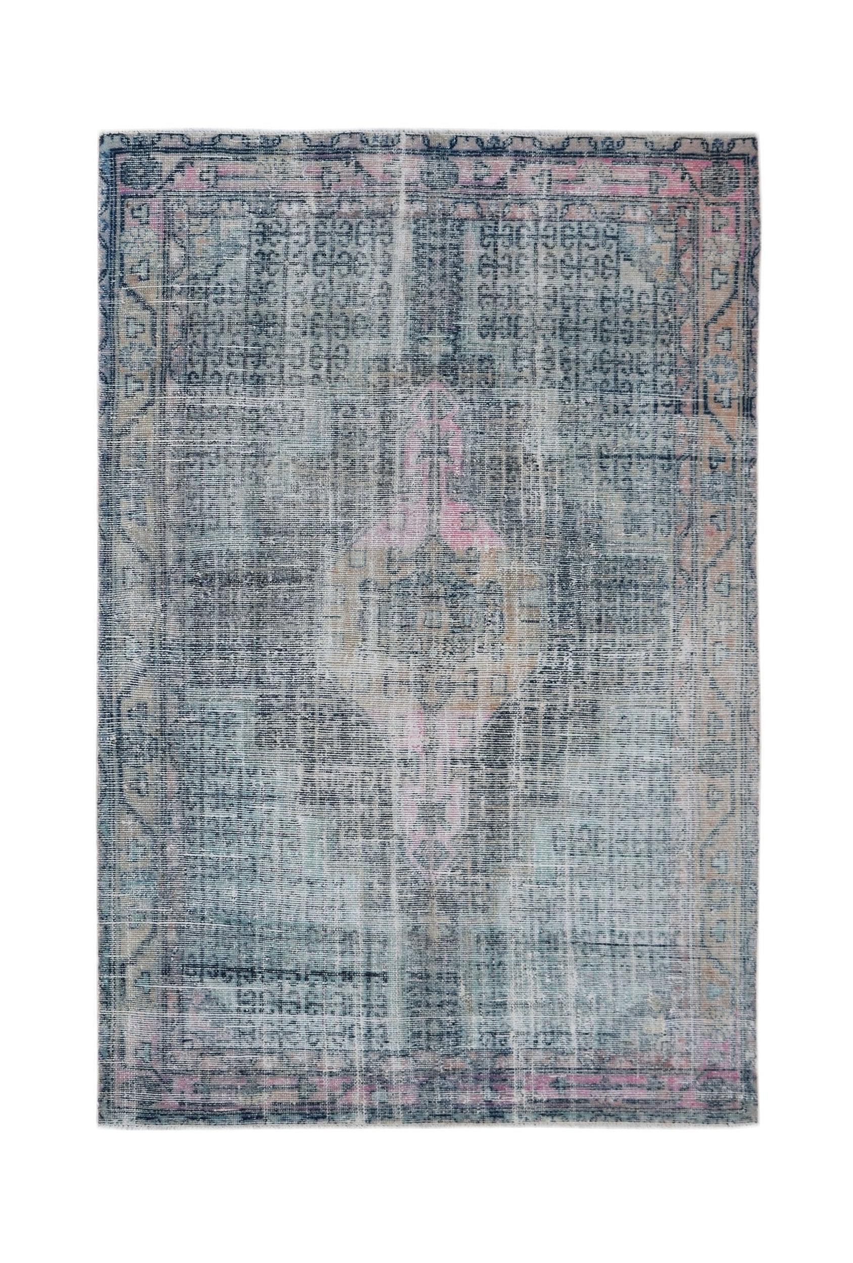 A vintage Persian rug featuring a faded blue and pink geometric pattern on a wool pile.