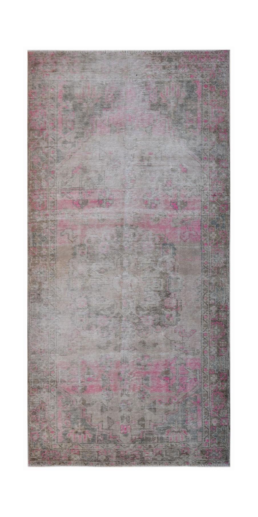 A vintage handwoven Persian rug featuring a faded floral pattern in shades of grey and pink.