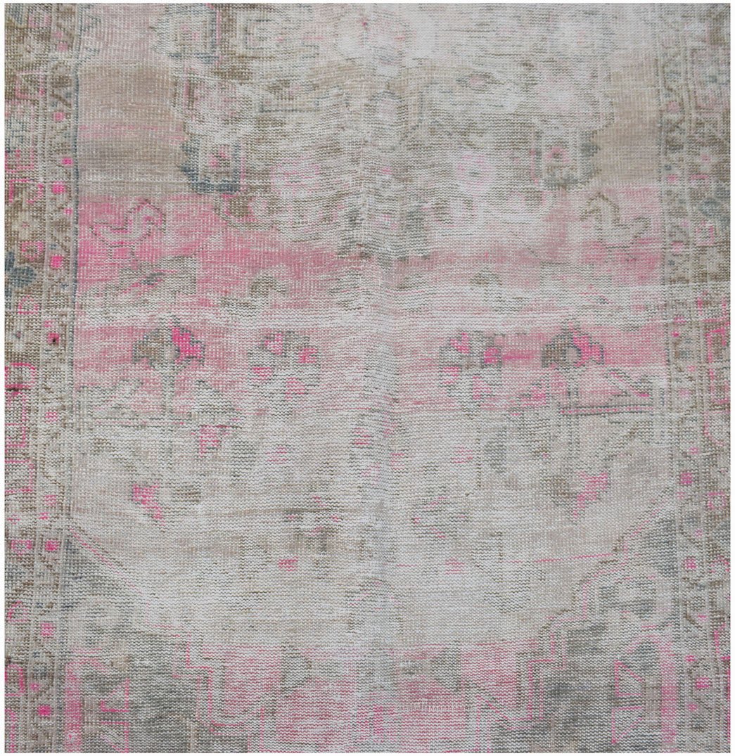 Vintage Persian rug with a distressed pink and grey pattern.