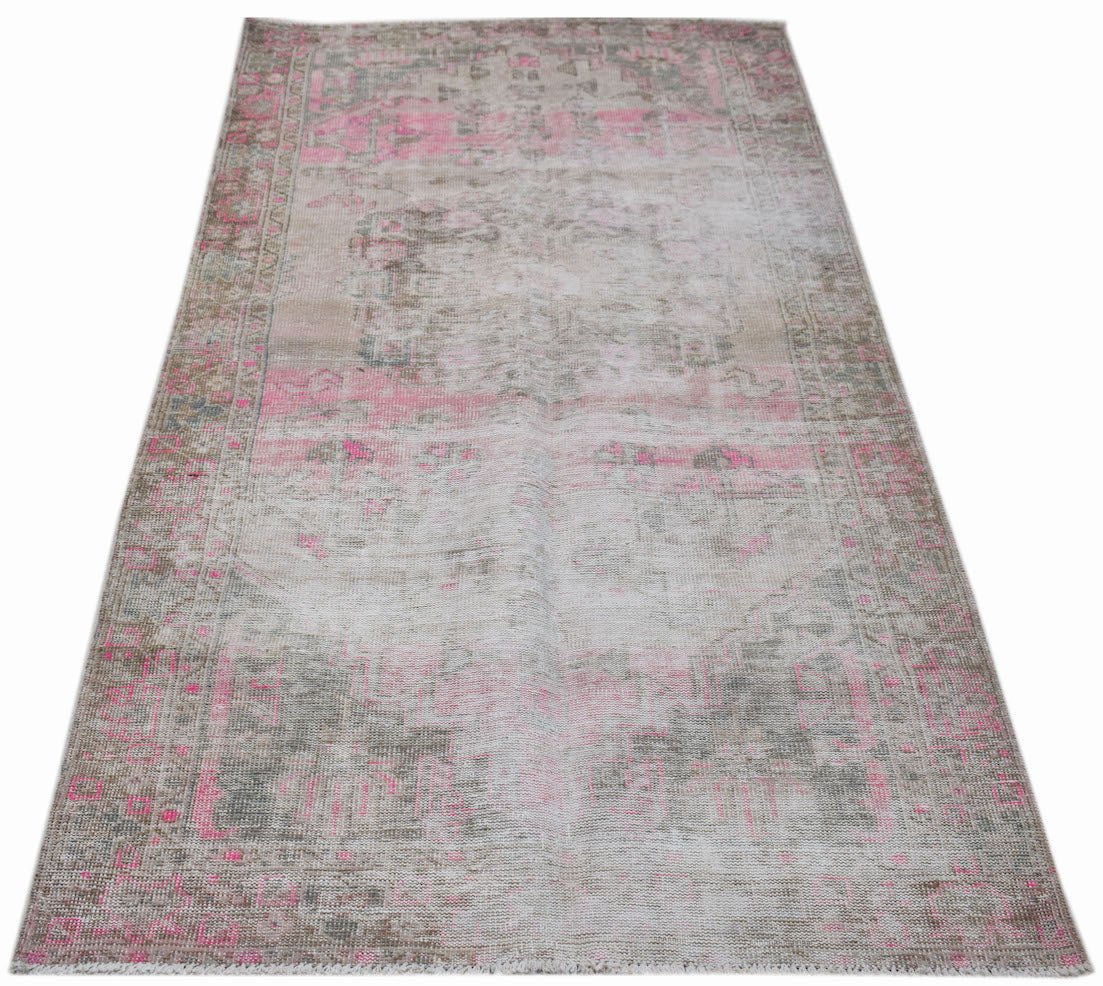 A vintage handwoven Persian rug featuring a faded, distressed pattern in shades of pink and grey.