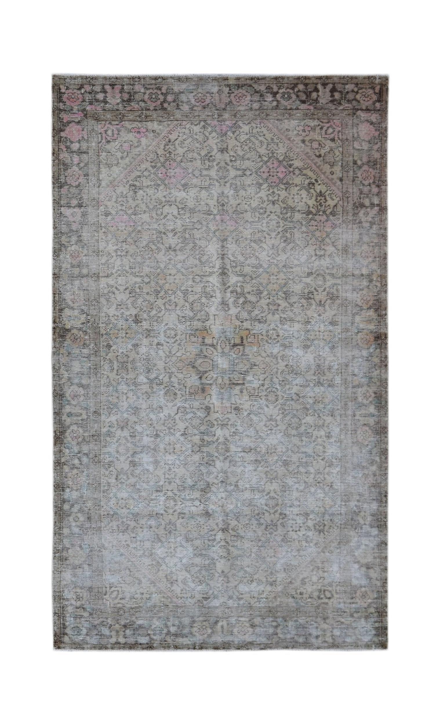 A vintage handwoven Persian rug featuring a faded floral pattern in muted grey and pink tones.