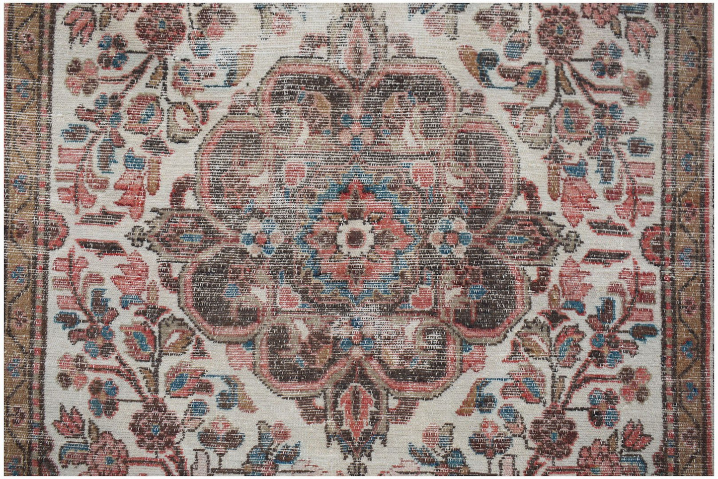 A vintage handwoven Persian rug featuring a central floral medallion in muted red and brown tones.