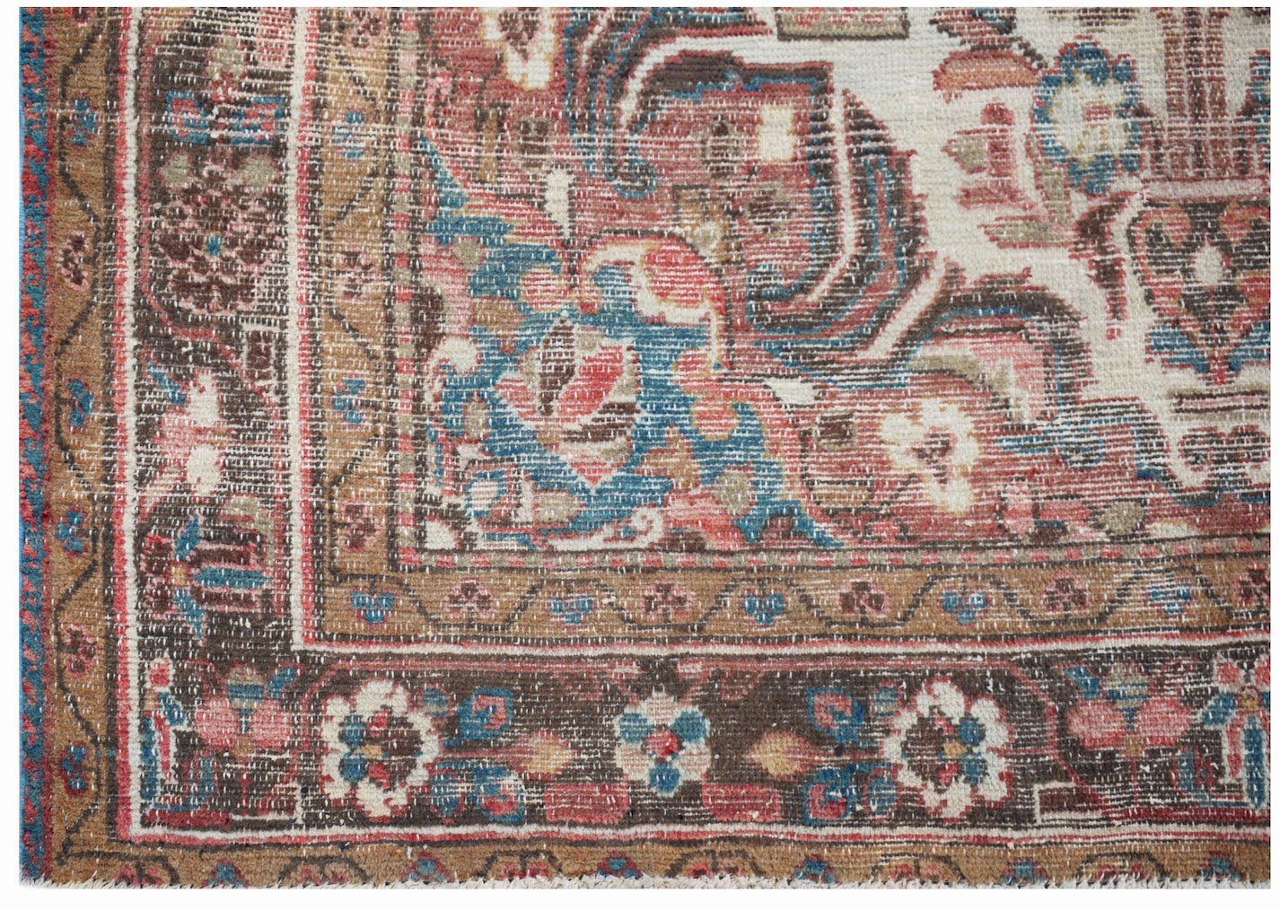 A handwoven vintage Persian rug featuring a floral pattern in faded red, blue, and brown tones.