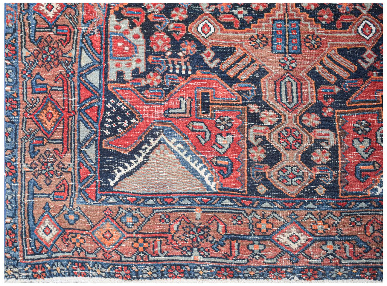 A handwoven vintage Persian rug featuring a geometric pattern in red, blue, and brown tones.