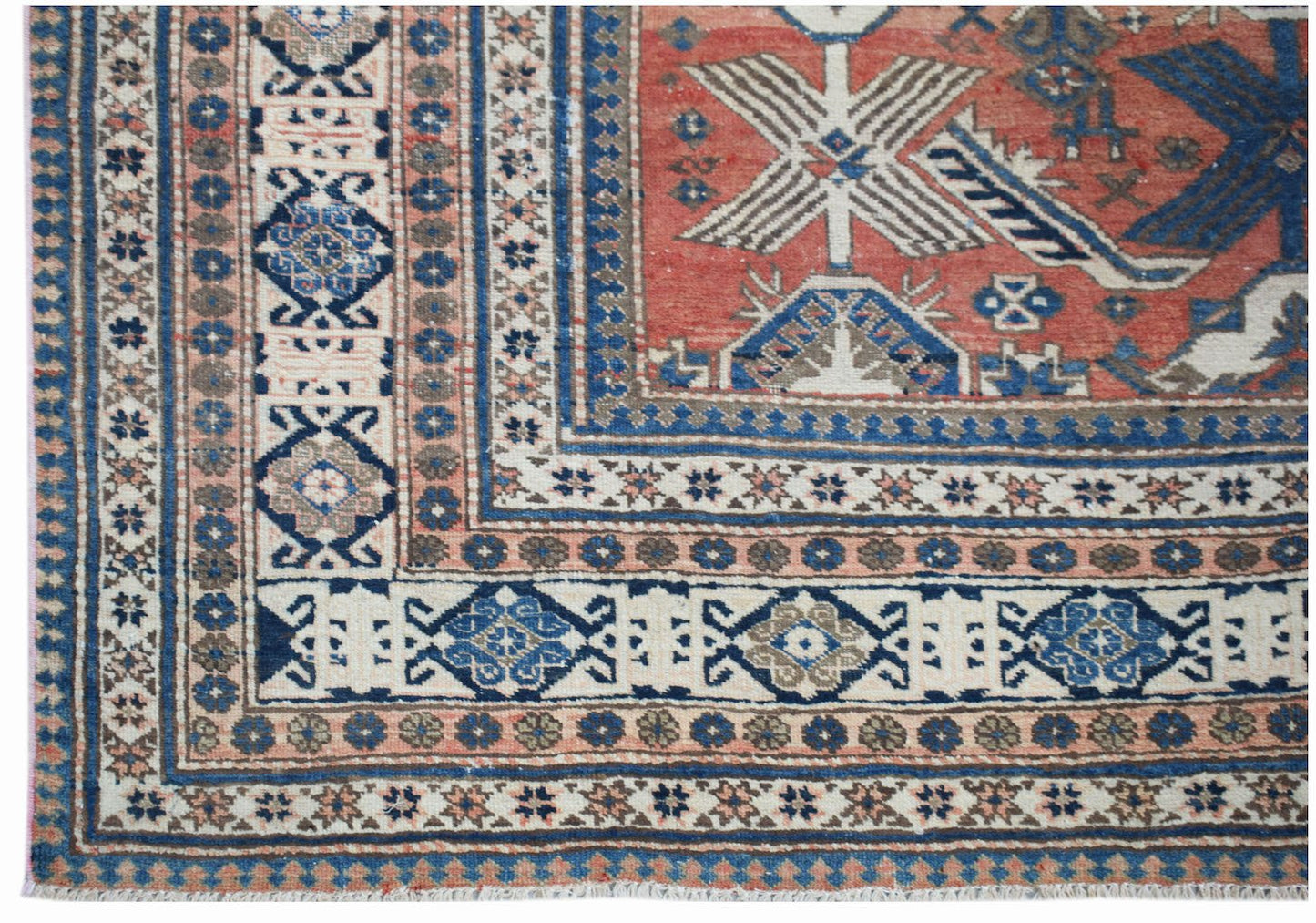 A handwoven vintage Persian rug featuring a geometric pattern in red, blue, and cream tones.