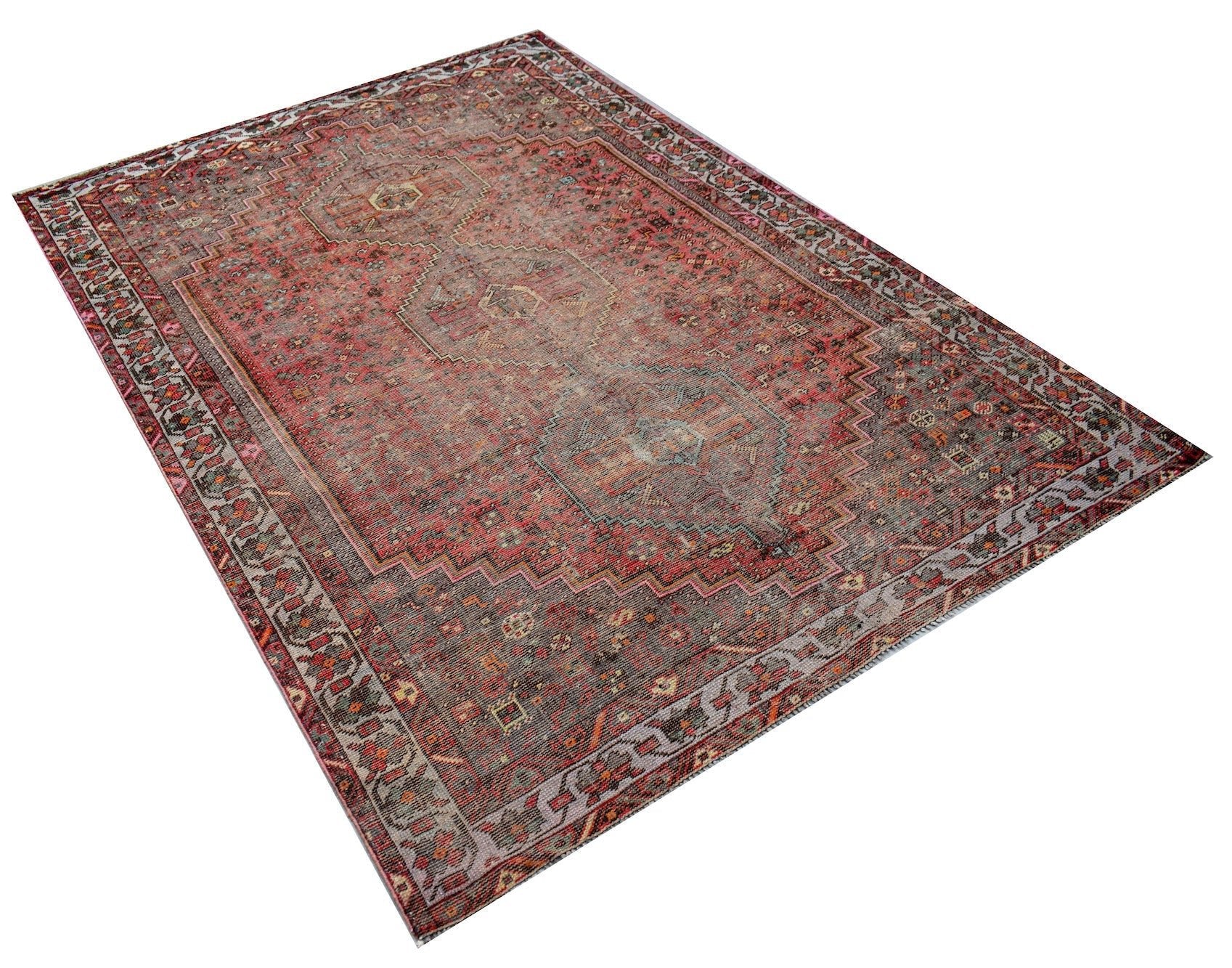 A rectangular vintage Persian rug featuring a faded red and grey traditional medallion pattern.