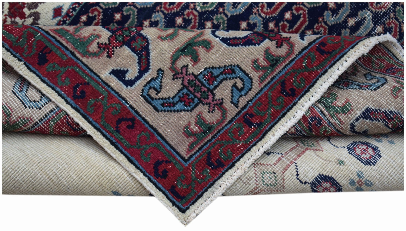 A folded vintage Persian rug featuring intricate floral patterns in red, blue, and beige tones.