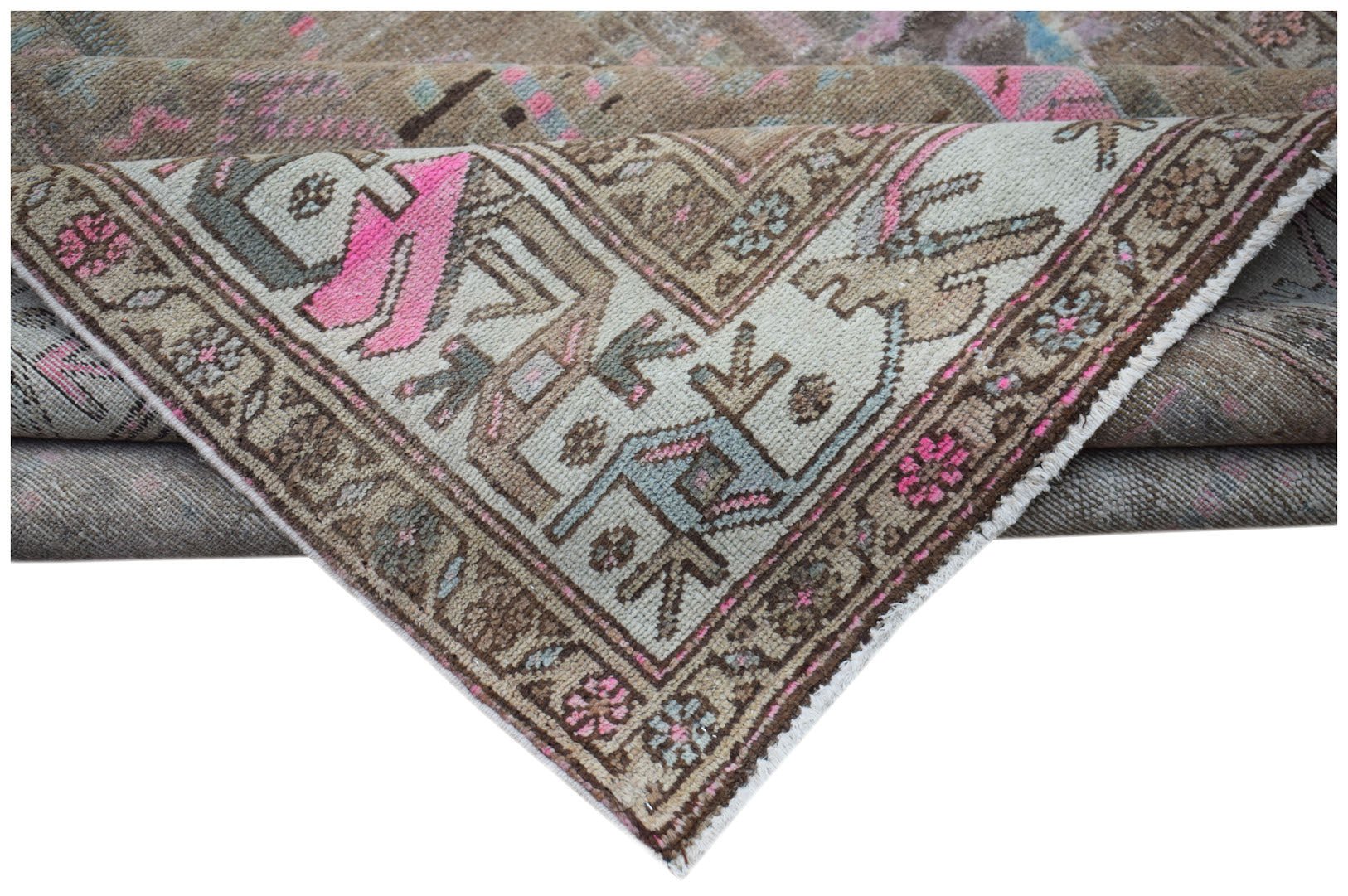 A vintage handwoven Persian rug featuring a faded geometric pattern in beige, pink, and blue.