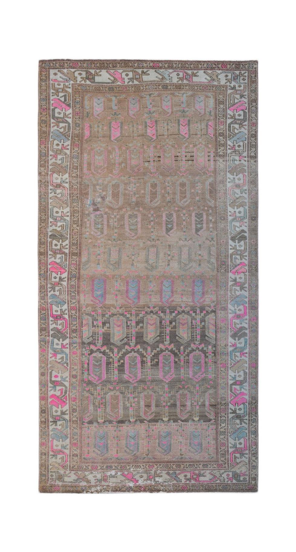 A vintage handwoven Persian rug featuring a geometric pattern in muted tones with pink accents.