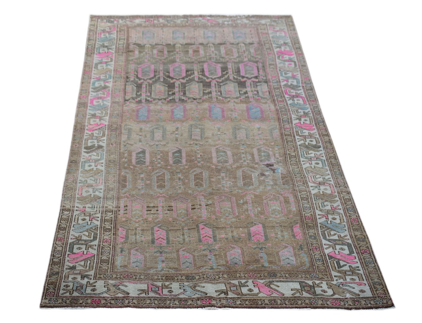 A vintage handwoven Persian rug featuring a faded brown field with pink and blue geometric motifs.
