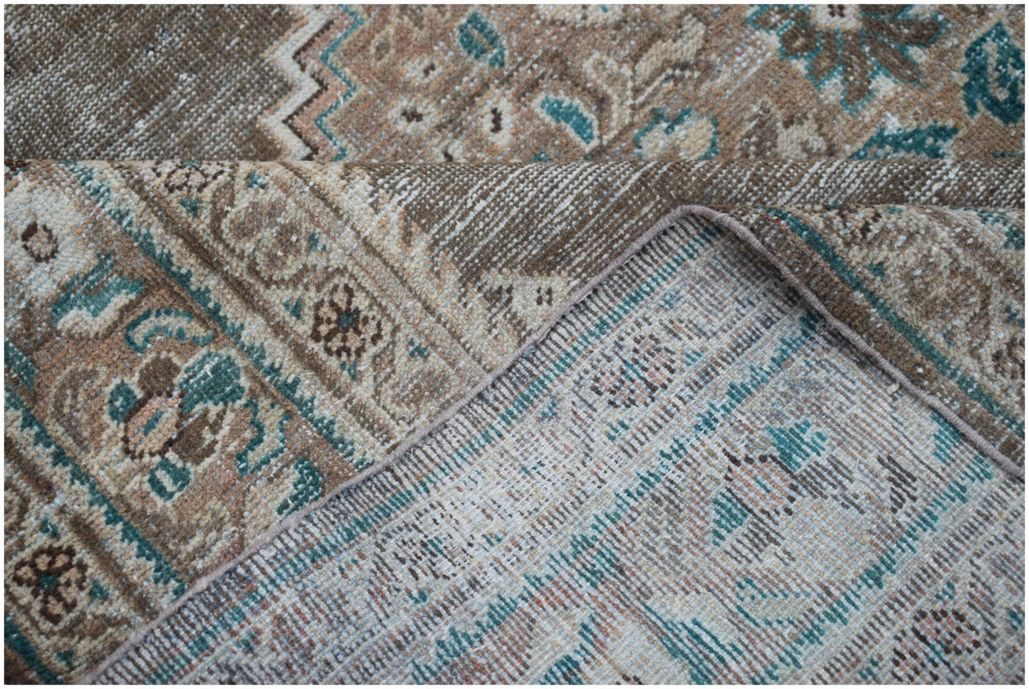 A vintage Persian Mahal rug featuring a faded floral pattern in shades of brown and teal.