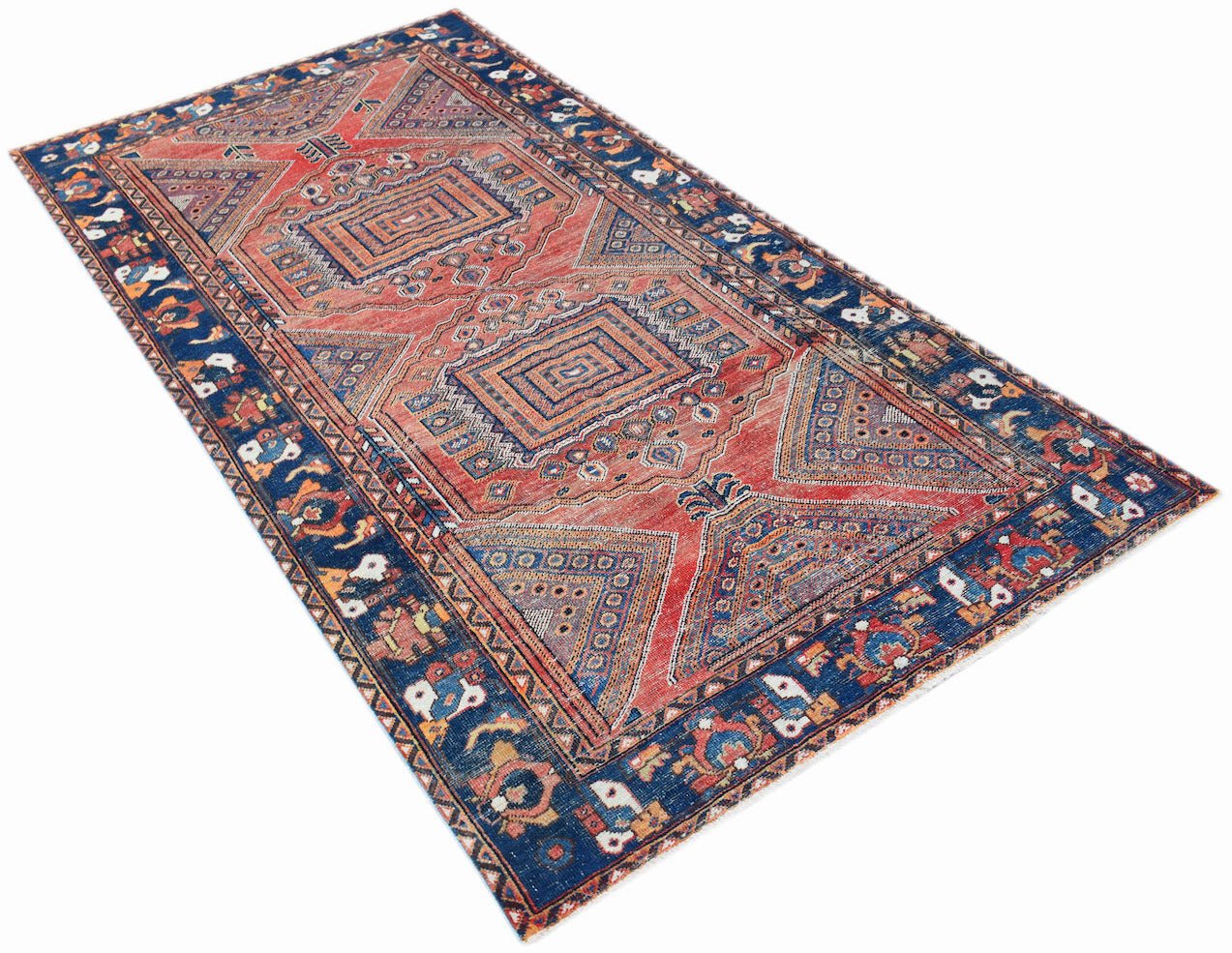 A handwoven vintage Persian rug featuring a geometric pattern in red and blue tones.